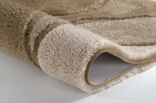 Beiger, flauschiger Badteppich in Nahaufnahme, teilweise aufgerollt