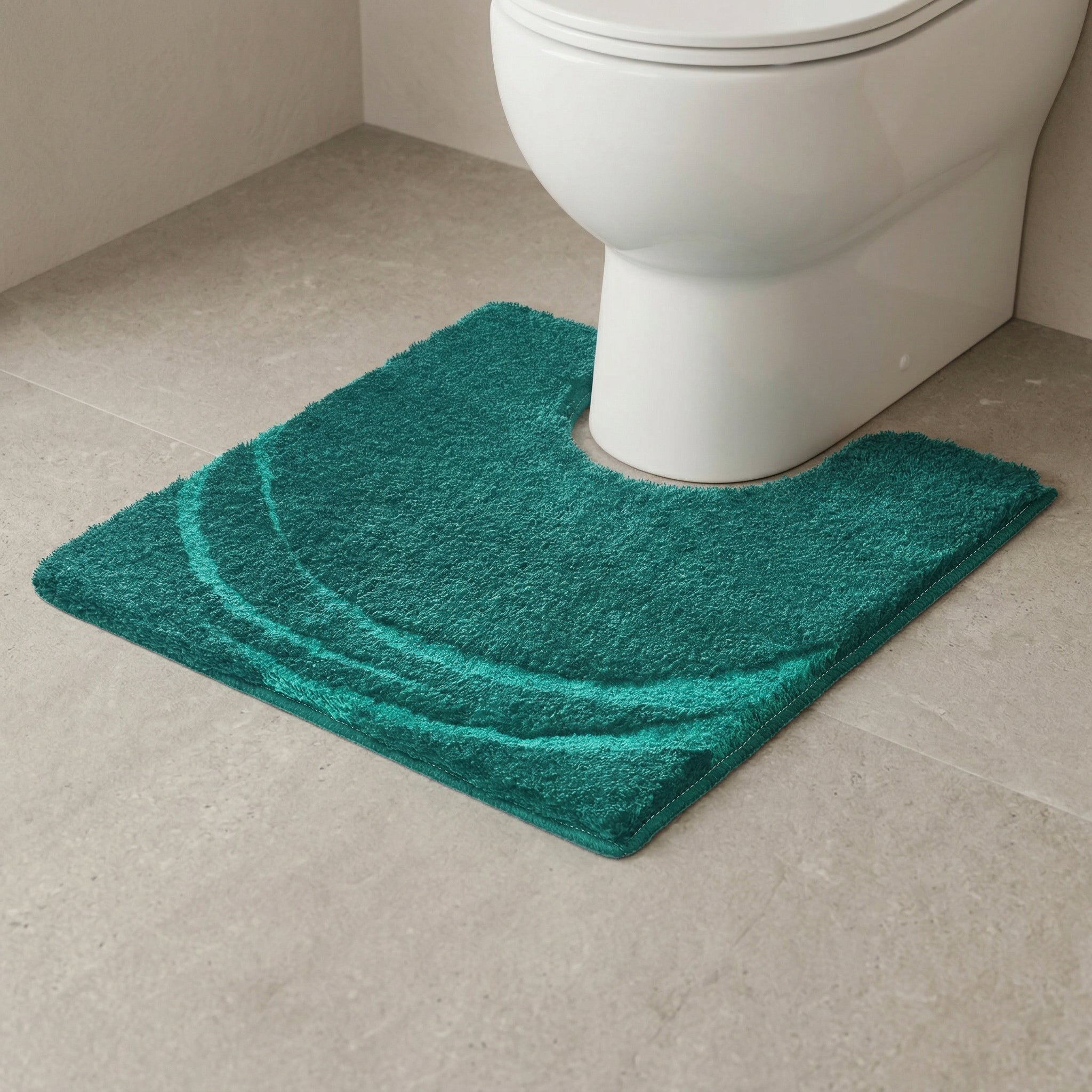 Grüne, halbmondförmig gemusterte WC-Vorlage vor weißer Toilette steht