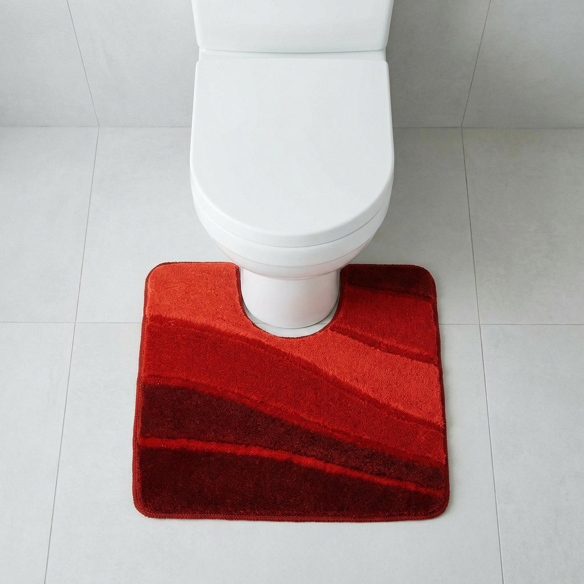 Weiße Toilette mit roter Badvorlage in Wellenoptik auf Fliesenboden