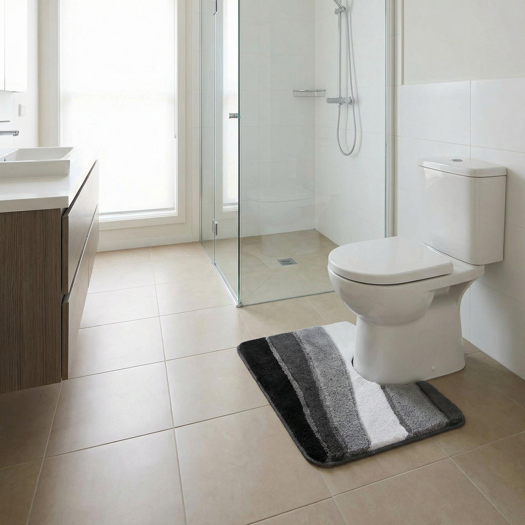 Modernes Badezimmer mit Toilette, Dusche und gestreifter Badematte