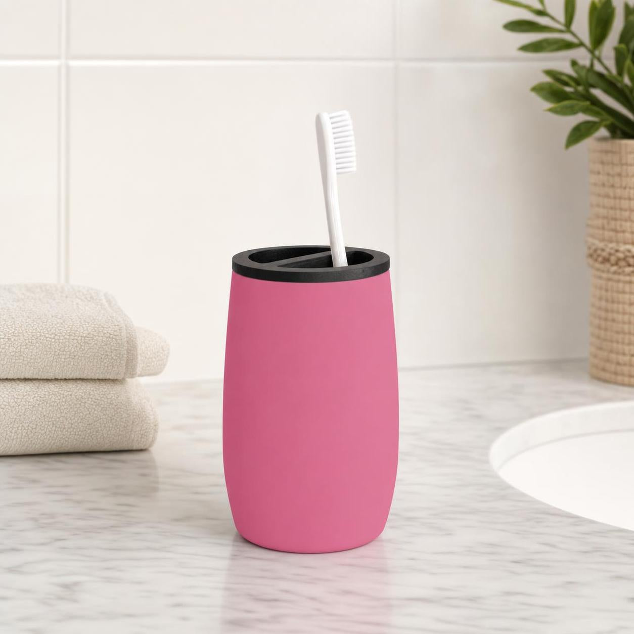 Ein rosa Zahnbürstenbecher mit Zahnbürste steht auf dem Waschbecken.