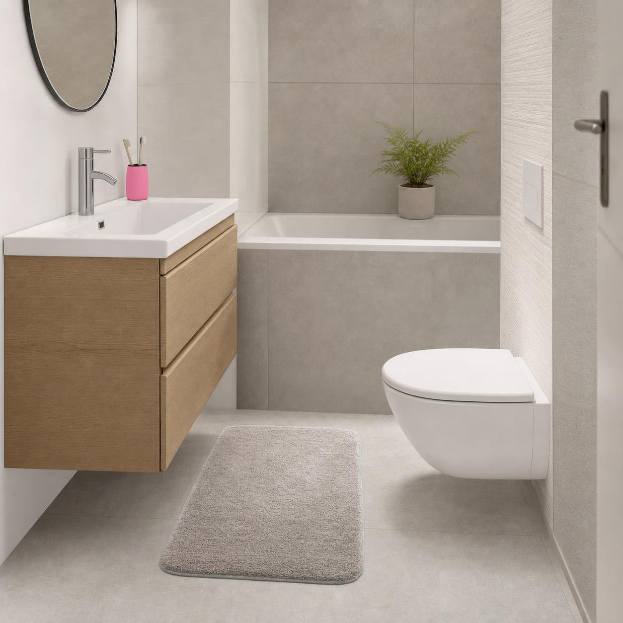 Graue Badematte liegt vor Waschbecken und WC im modernen Bad.