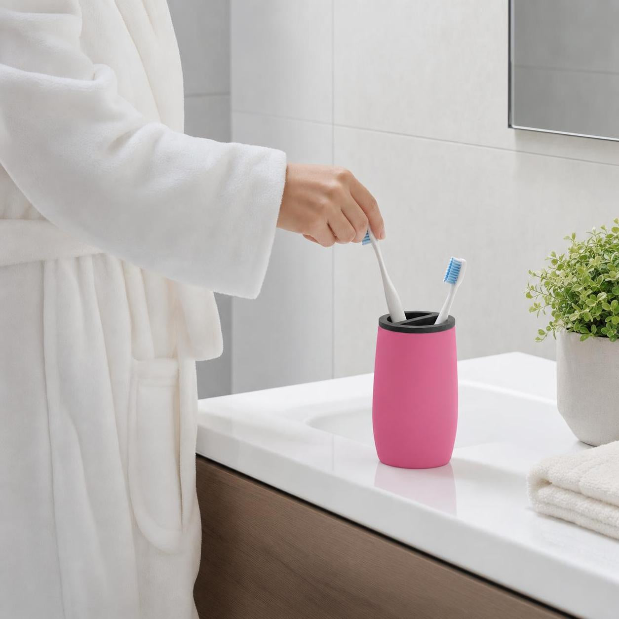 Ein pinker Zahnbürstenhalter steht mit Bürsten auf dem Waschbecken.