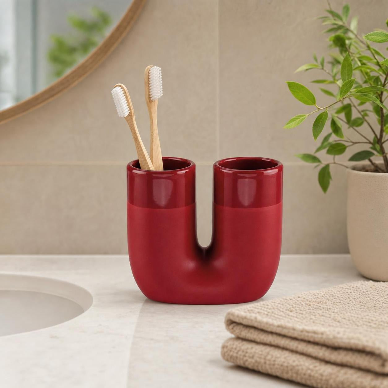 Roter Doppel-Zahnputzbecher mit Bambuszahnbürsten am Waschbecken.
