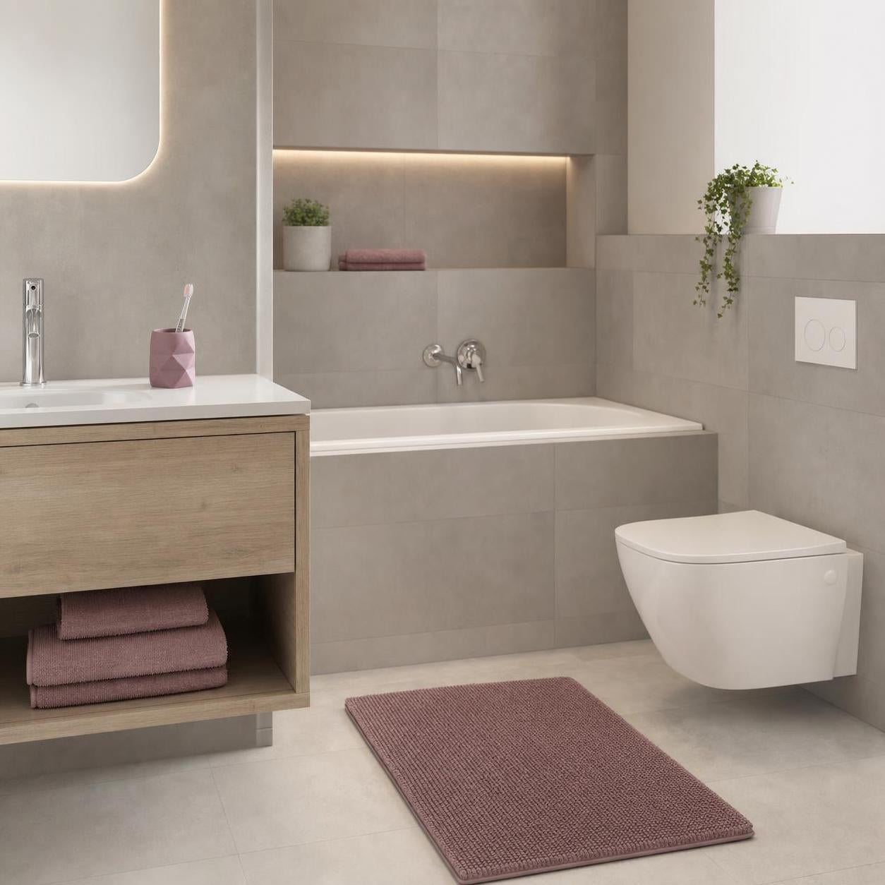 Rosa Badteppich liegt vor Badewanne und WC in modernem Badezimmer.