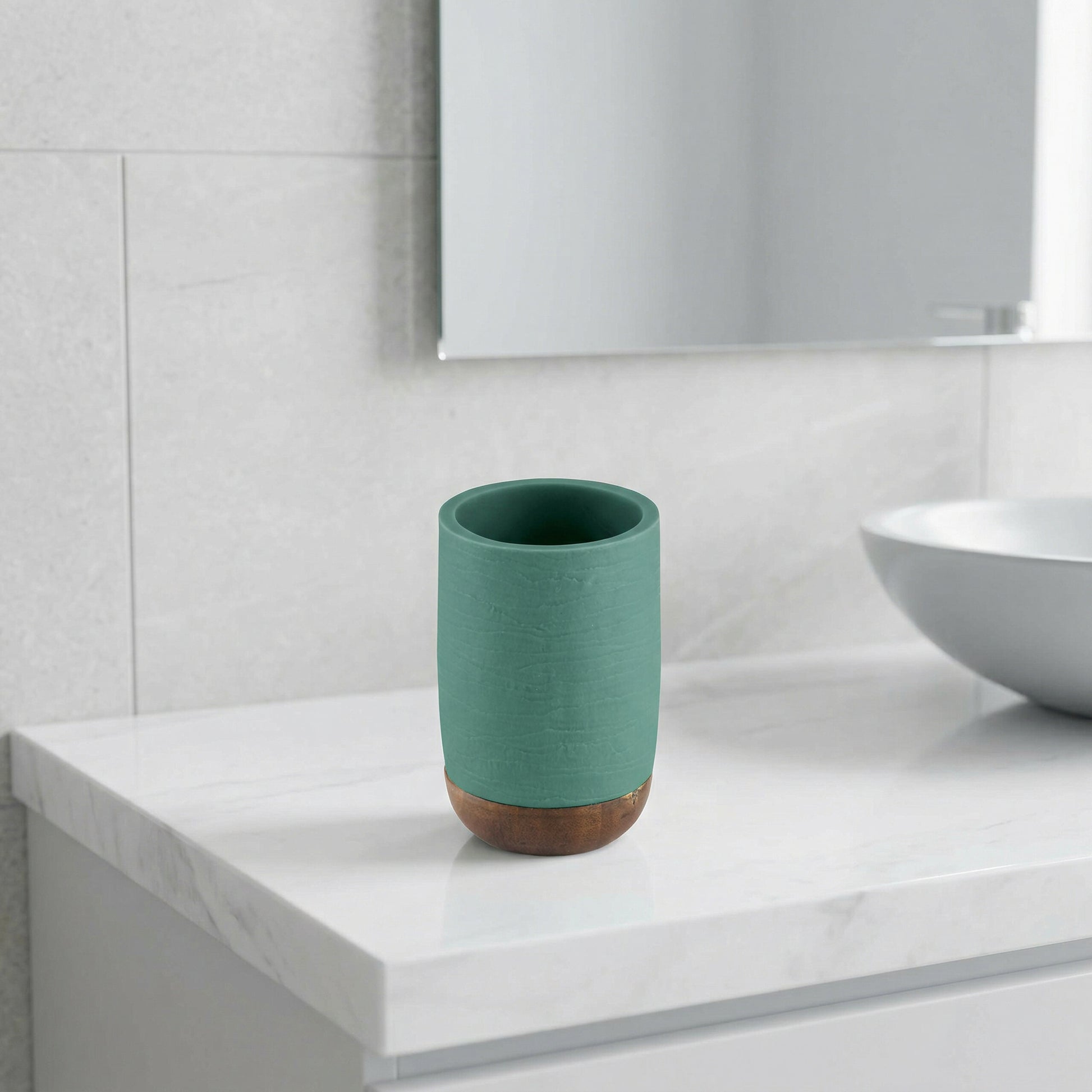 Grüner Zahnputzbecher mit Holzfuß auf weißer keramischer Badezimmerablage