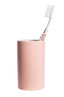 Rosa Zahnputzbecher aus Keramik mit weißer Zahnbürste stehend auf Weiß