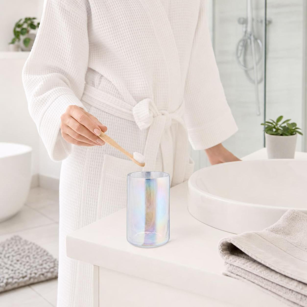 Schimmernder Zahnputzbecher steht neben dem Waschbecken im Bad.
