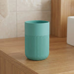 Türkiser Zahnputzbecher mit Rillenstruktur auf Holzwaschtisch stehend