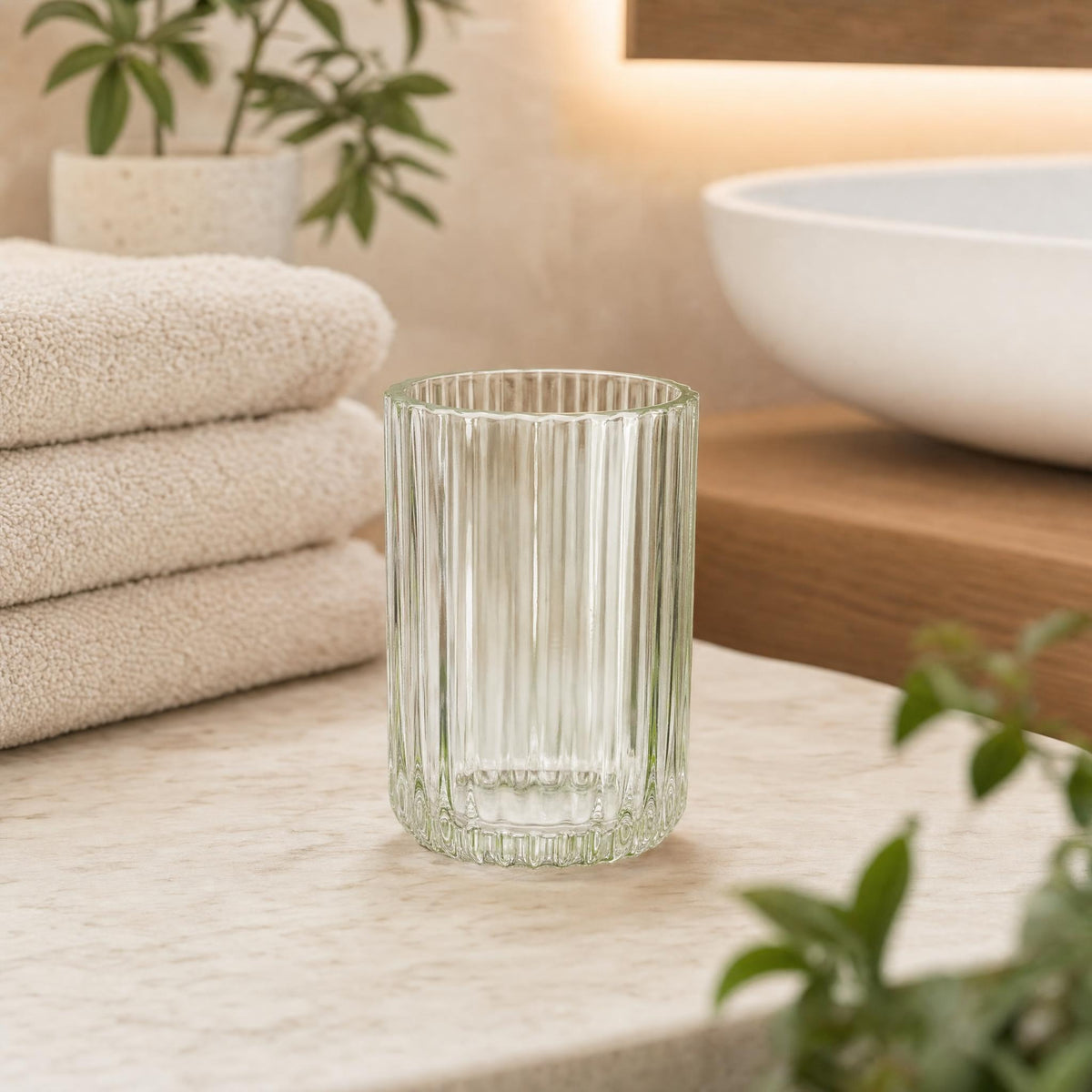 Geriffeltes Glas auf Waschtisch neben Handtüchern und Waschbecken.
