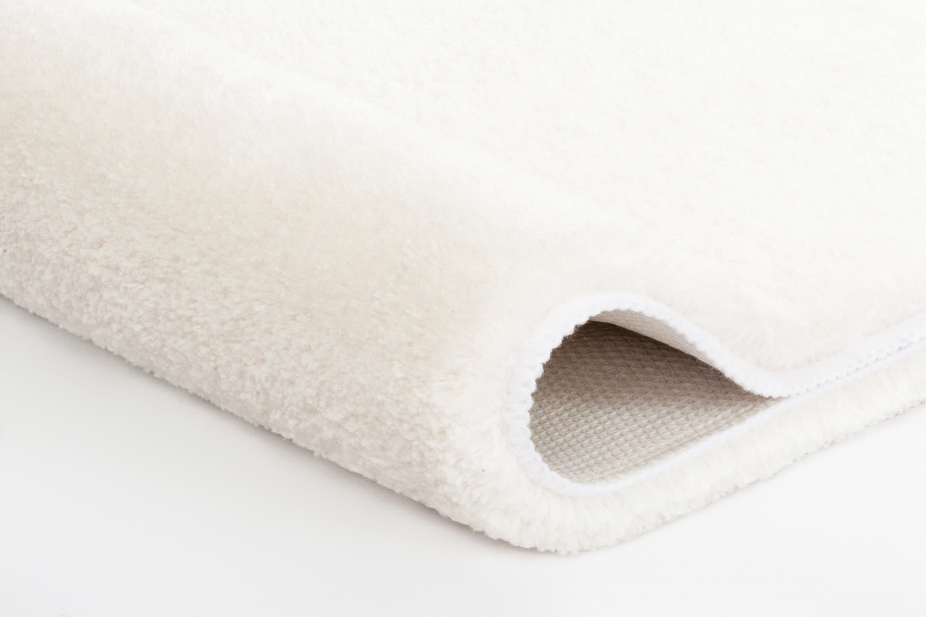 Weißer, flauschiger Badteppich mit rutschfester Unterseite, ideal für ein gemütliches und sicheres Badezimmer.