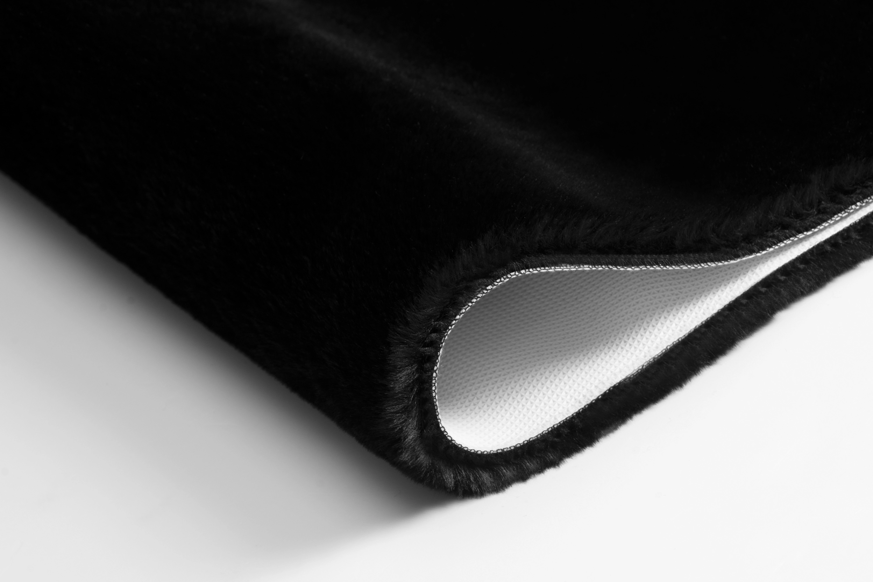 Schwarzer, flauschiger Teppich mit rutschfester Unterseite, ideal für Badezimmer und Wohnräume.
