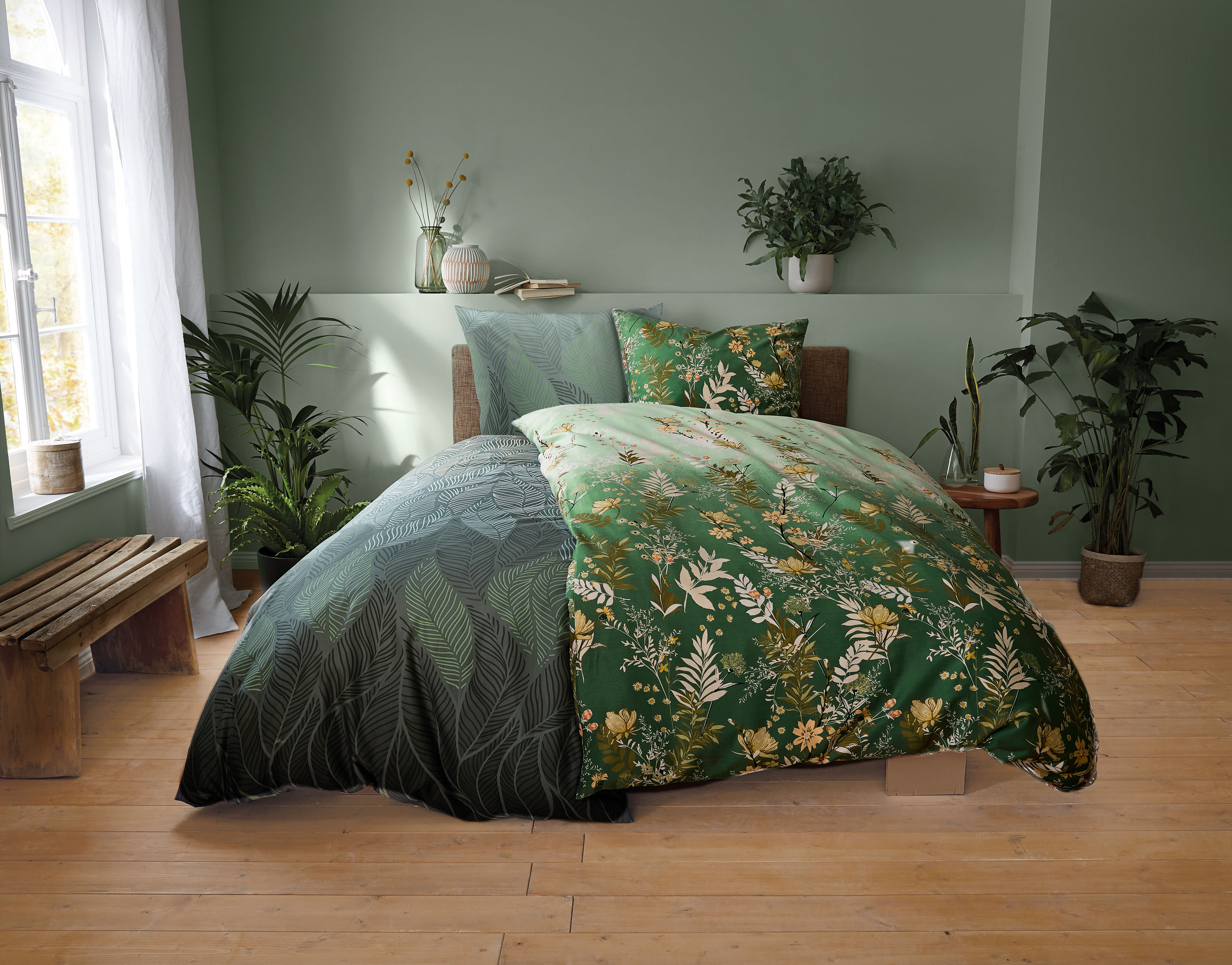 Grüne Bettwäsche mit floralem Muster in modernem Schlafzimmer mit Pflanzen und Holzboden.