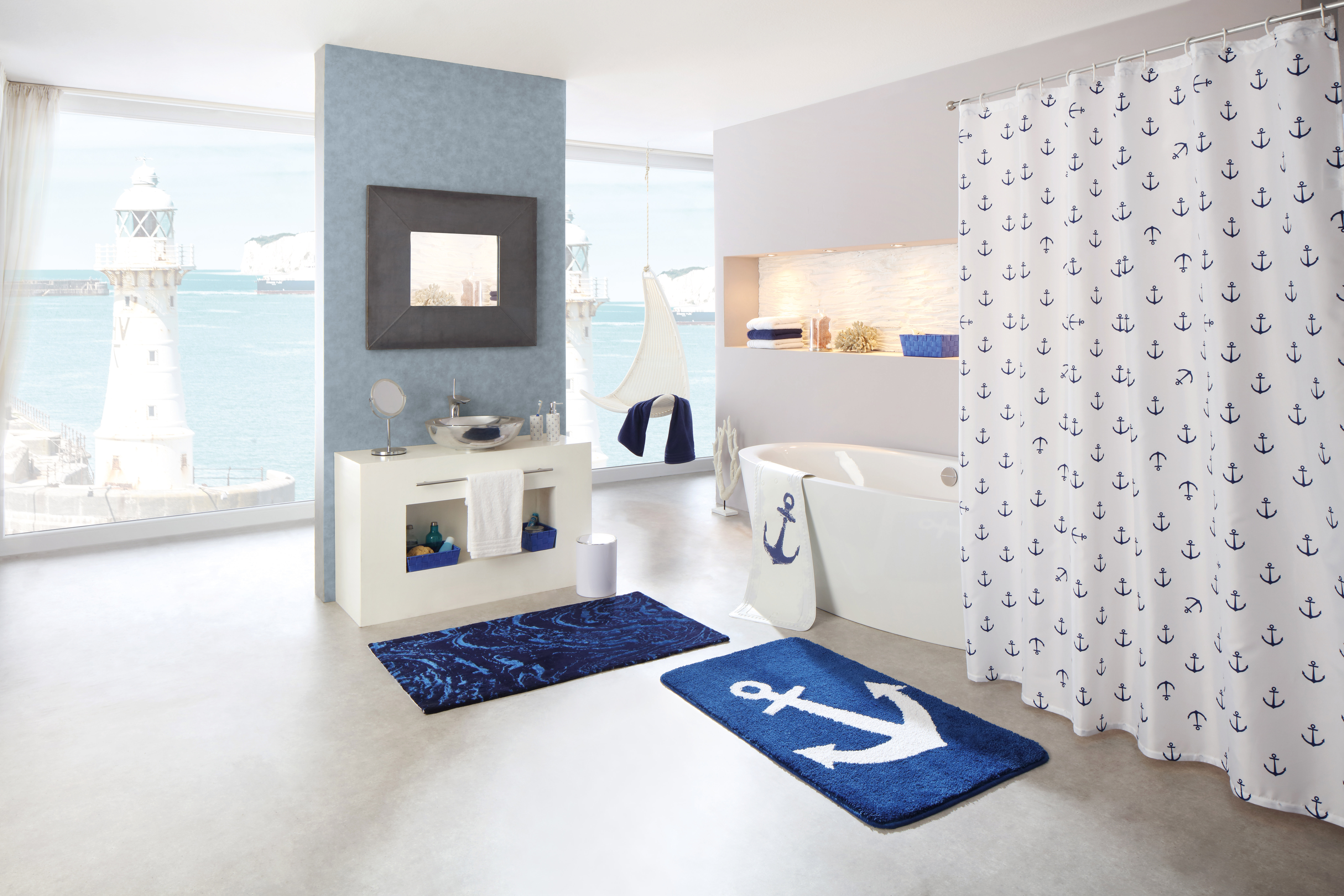 Maritimes Badezimmer mit Anker-Dekor: Duschvorhang, Teppiche und Accessoires in Blau und Weiß, mit Blick auf den Leuchtturm.