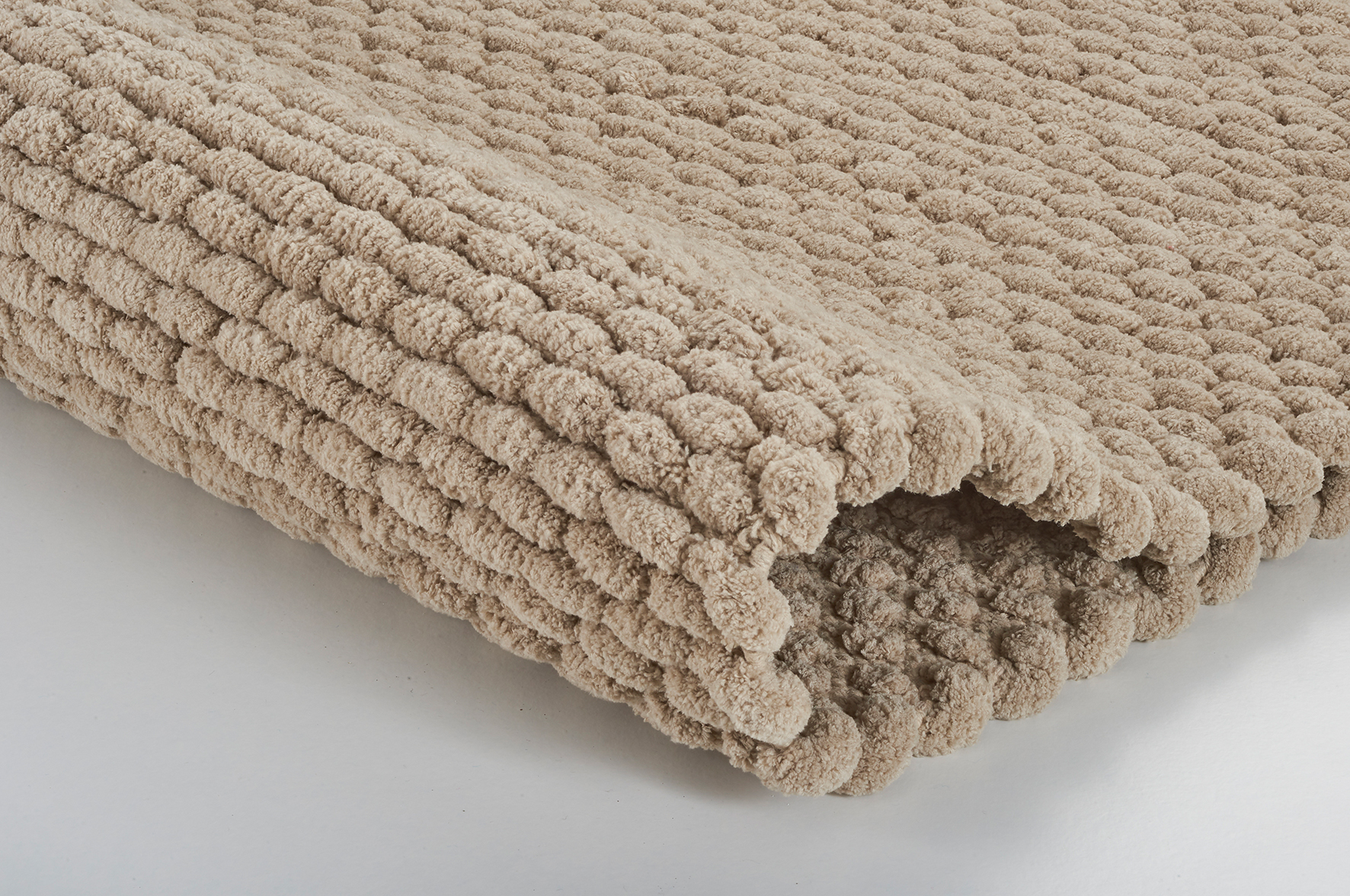 Beige Badematte mit weicher, strukturierter Oberfläche, ideal für ein gemütliches Badezimmerambiente.