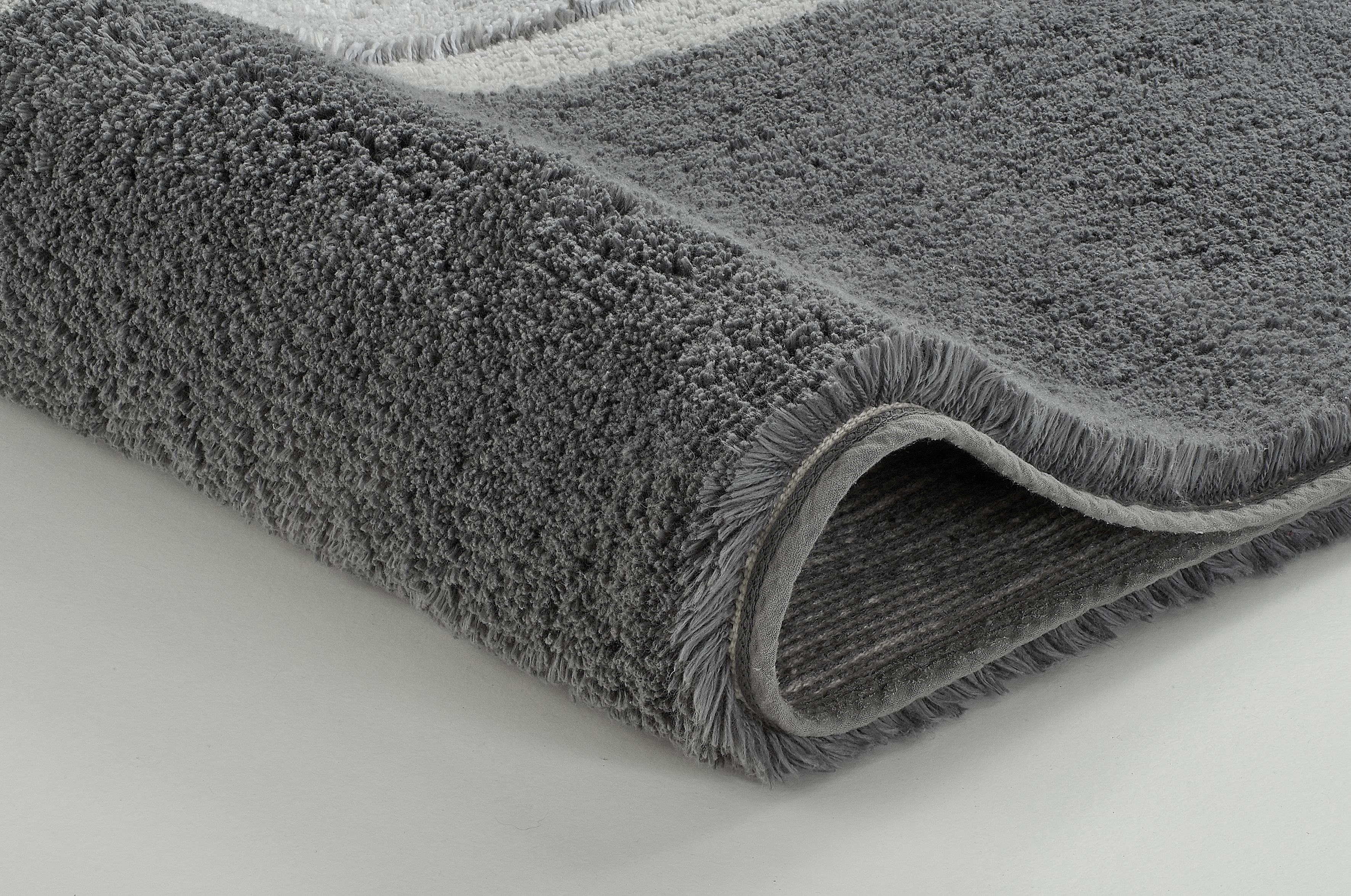 Grauer, flauschiger Badezimmerteppich mit weicher Textur und rutschfester Unterseite, ideal für ein gemütliches Badezimmer.