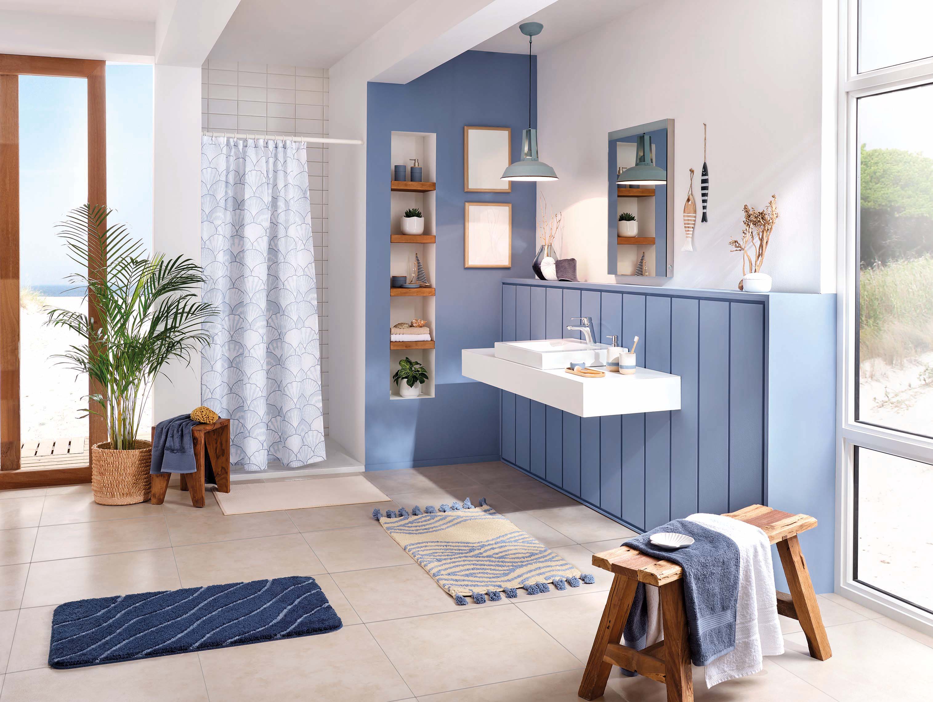 Modernes Badezimmer mit maritimen Akzenten, blauen und weißen Elementen, Holzdetails und Blick auf den Strand.