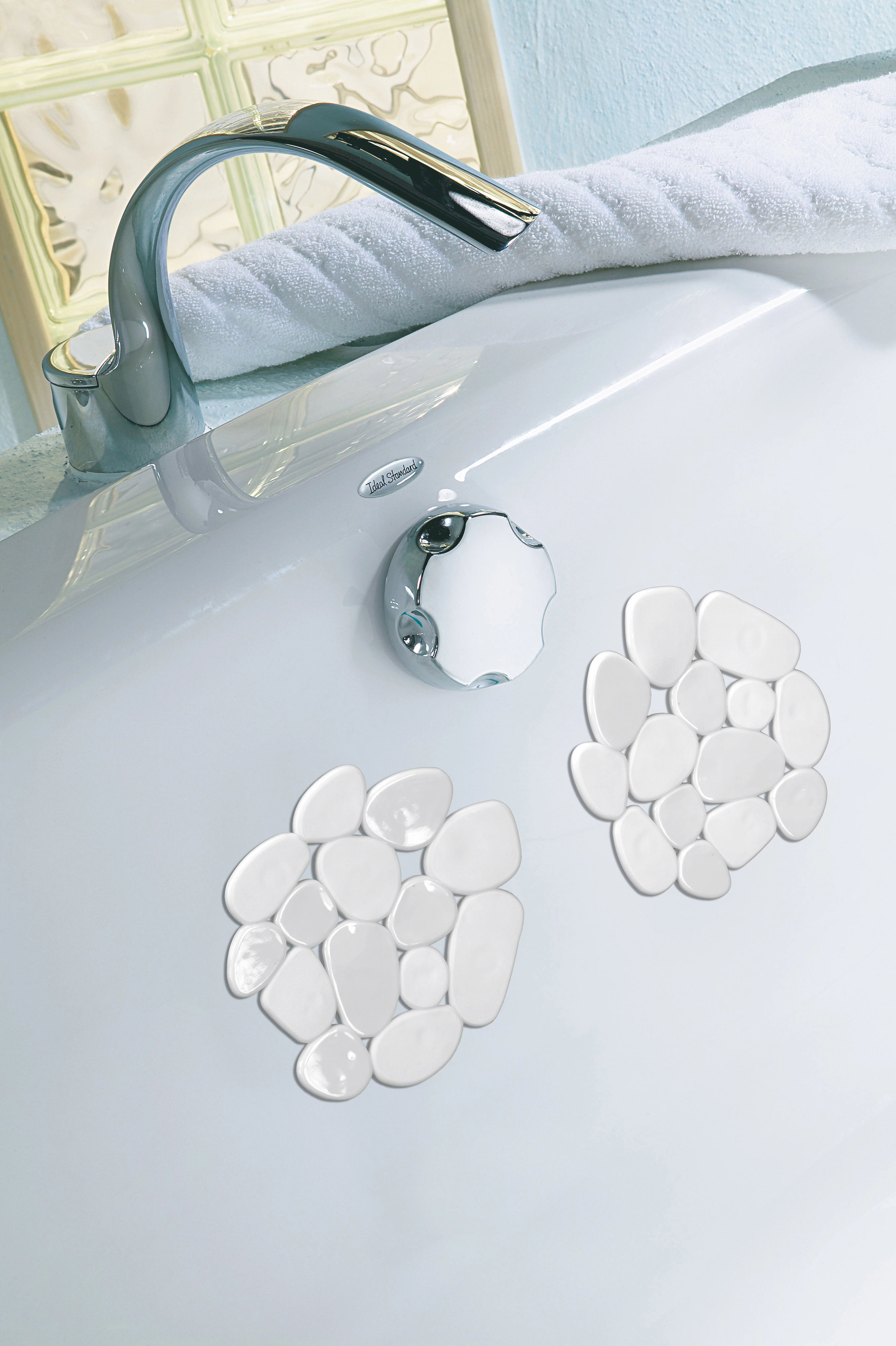 Deko-Minis SASSOLINO Weiß Set 6-teilig Antirutsch-Aufkleber in Kieselstein-Optik auf einer Badewanne, mit Wasserhahn und Handtuch im Hintergrund.