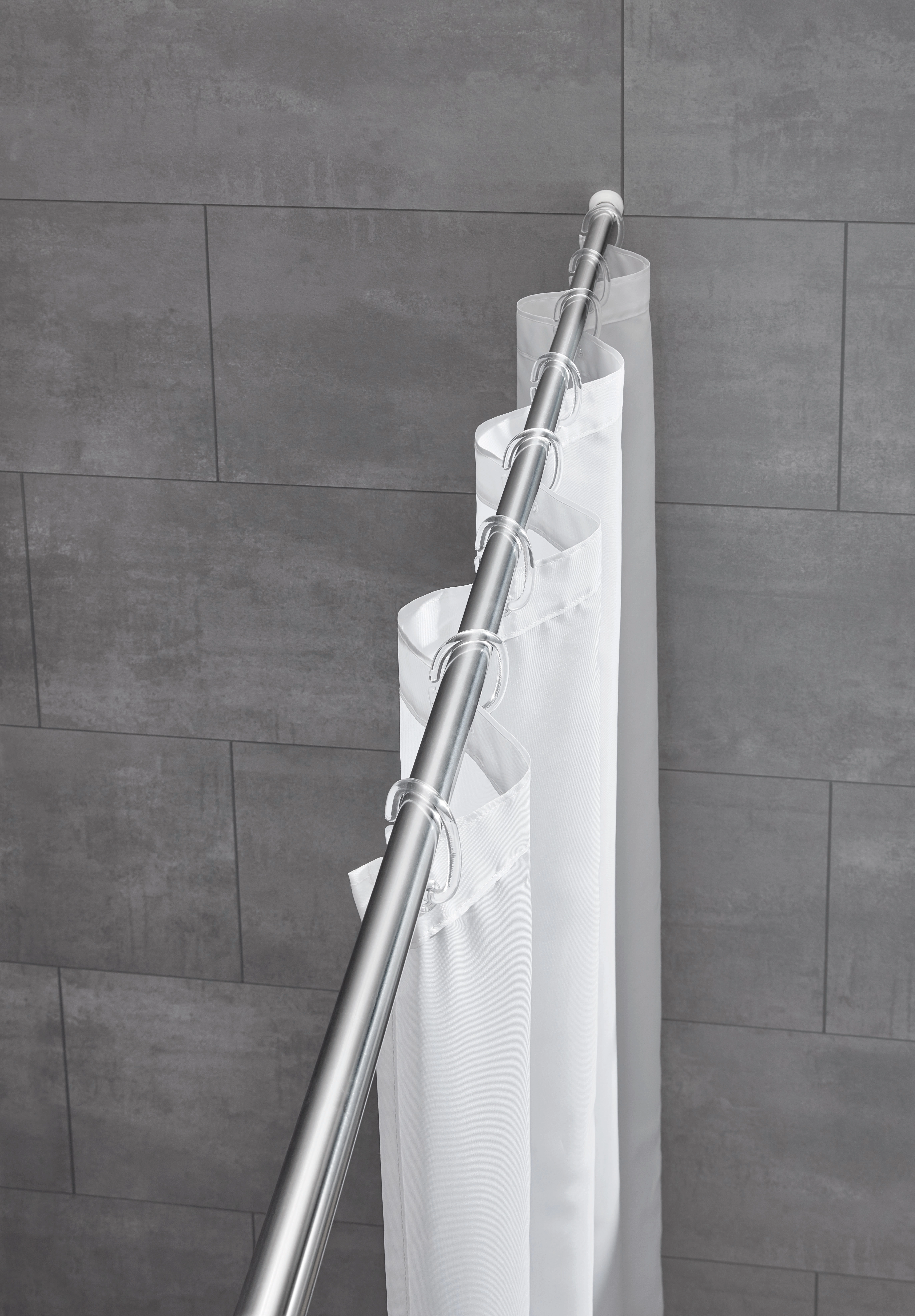 Duschvorhangstange aus Chrom mit weißen Ringen und Vorhang, montiert vor grauen Fliesen.
