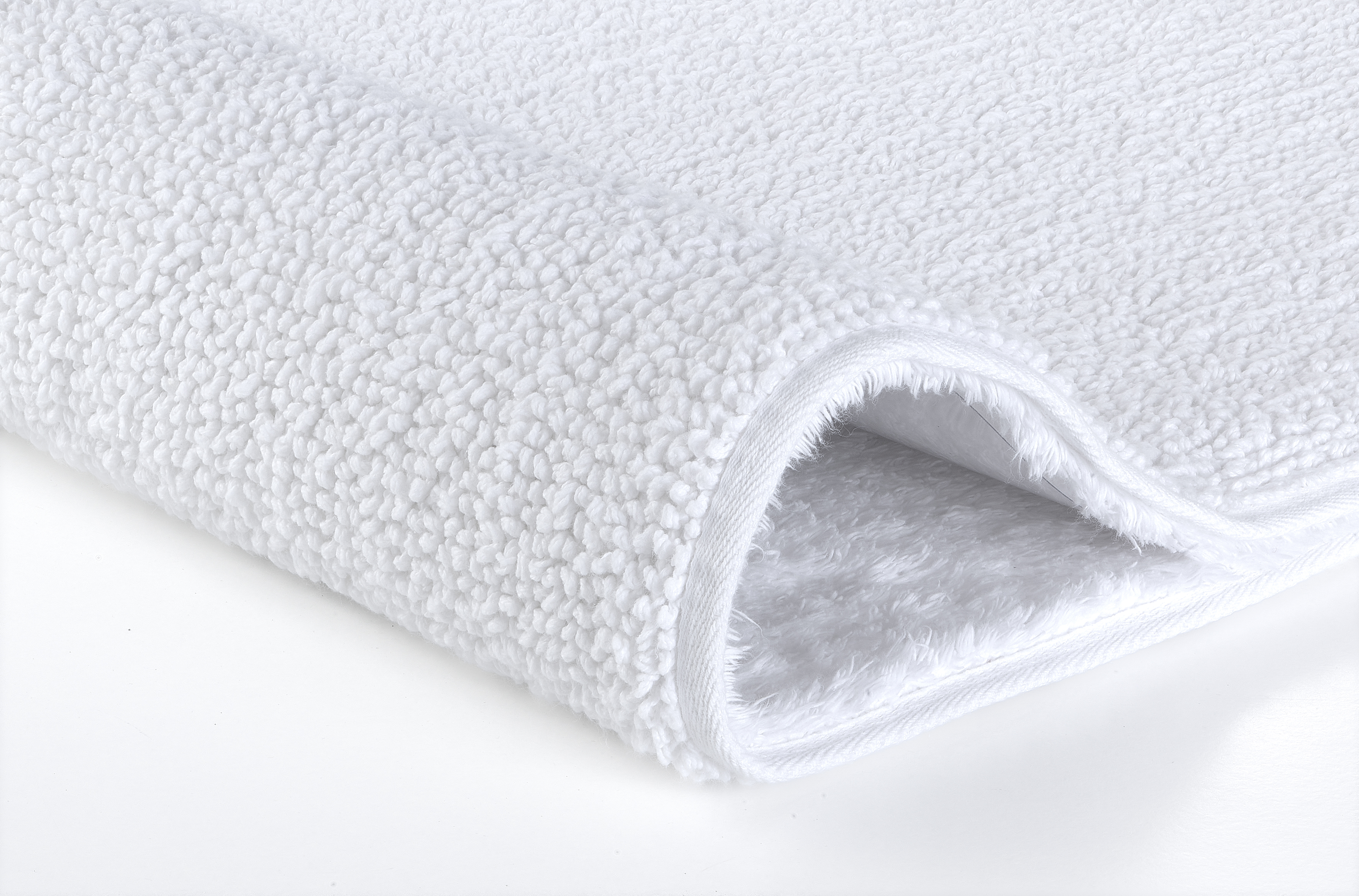 Weißer, flauschiger Badteppich mit weicher, strukturierter Oberfläche und rutschfester Unterseite. Ideal für jedes Badezimmer.