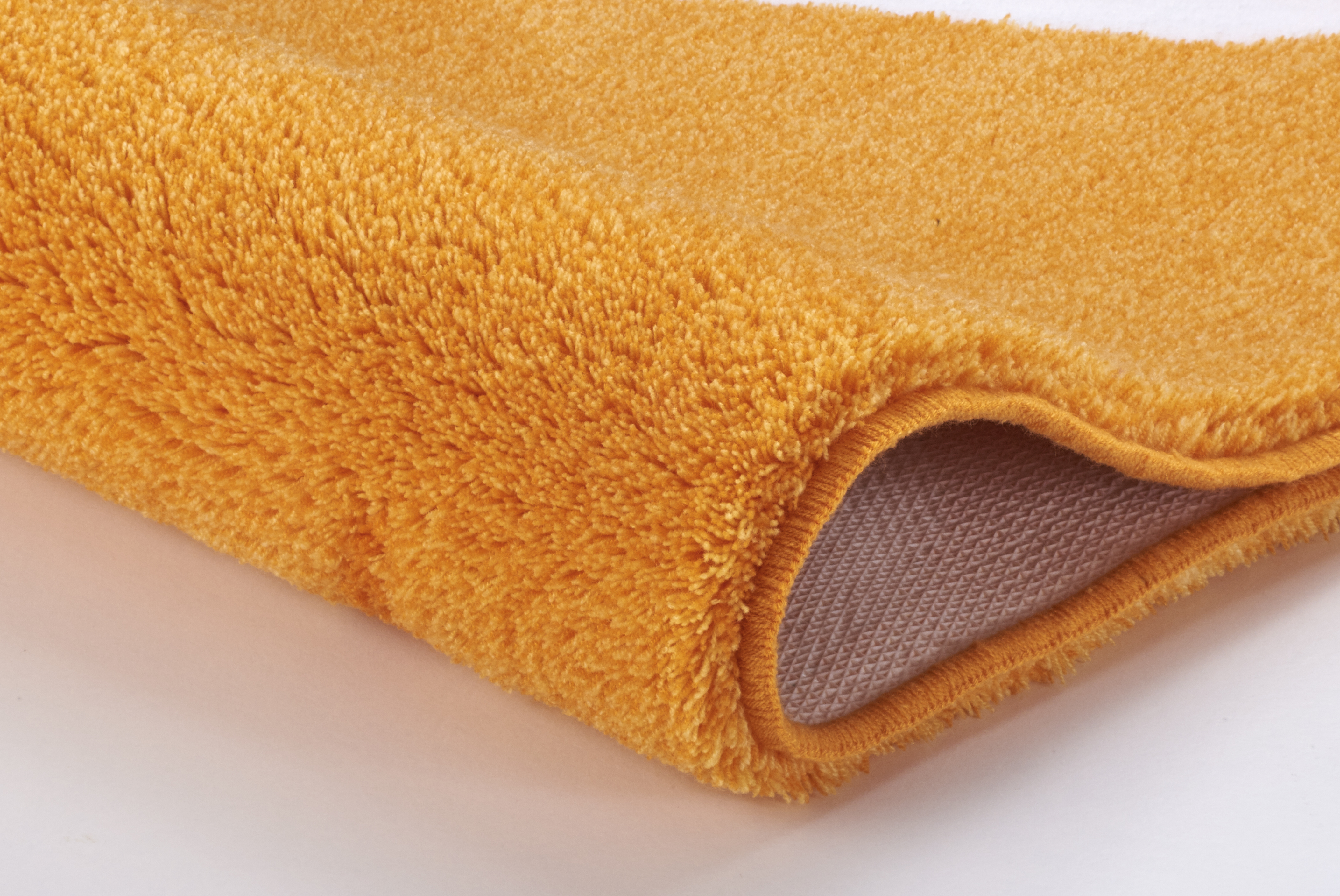 Weicher, orangefarbener Badteppich mit rutschfester Unterseite, ideal für ein gemütliches Badezimmer.