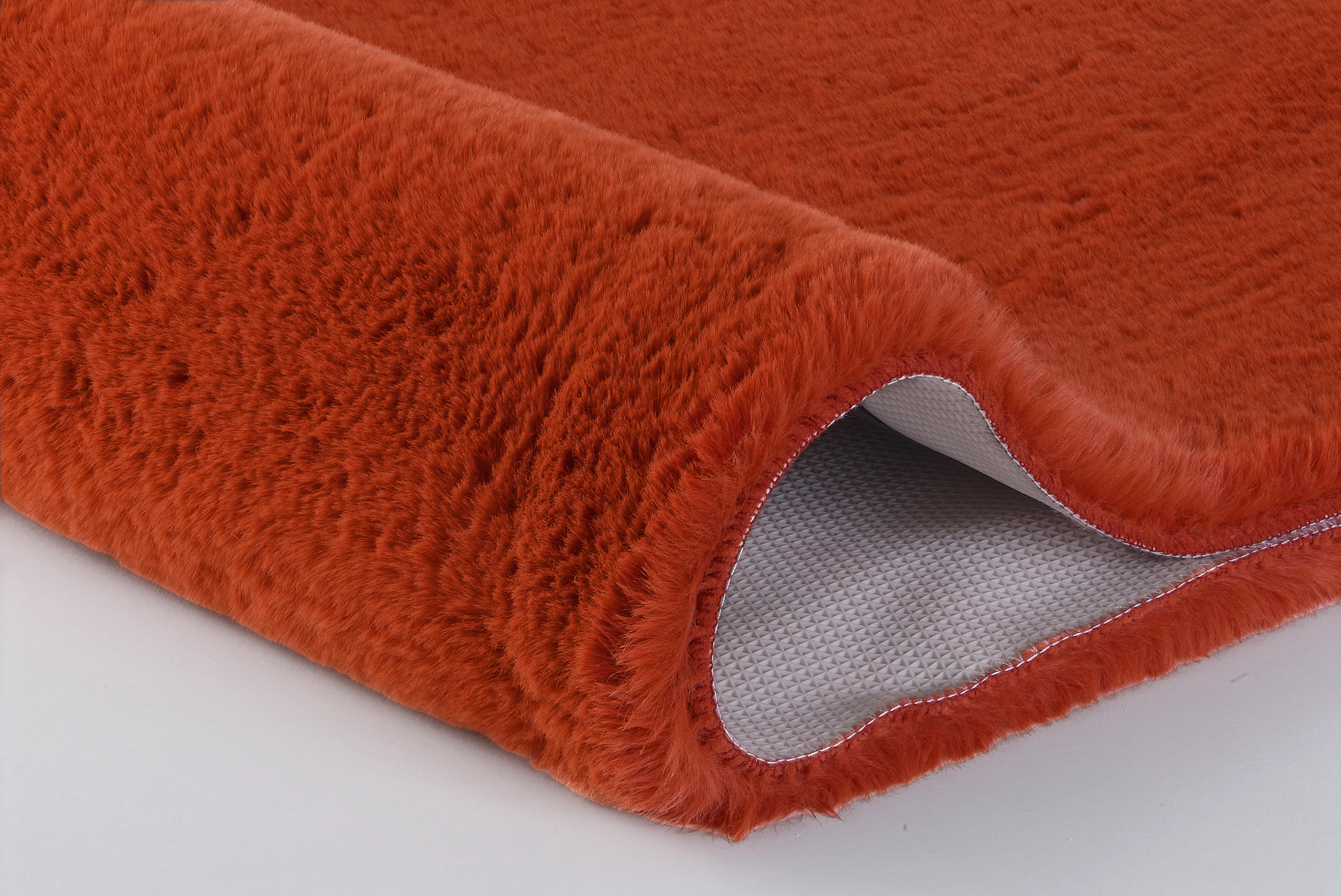 Weicher, orangefarbener Teppich mit rutschfester Unterseite, ideal für Wohn- und Schlafzimmer.
