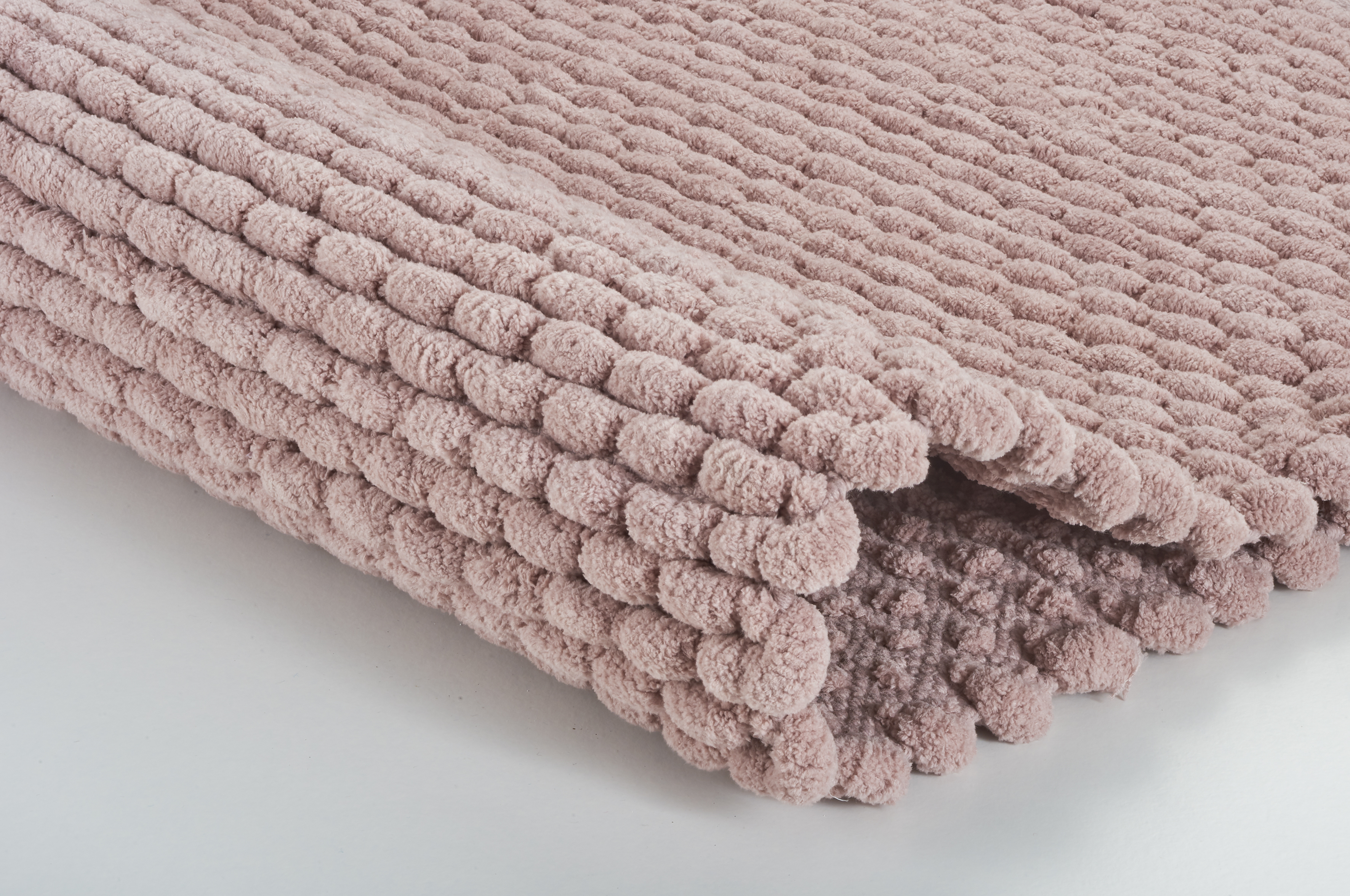 Weiche, rosa Badematte mit strukturierter Oberfläche, ideal für ein gemütliches Badezimmerambiente.