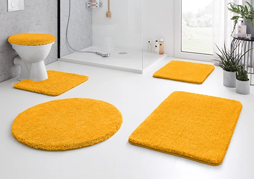 Badezimmer-Set in leuchtendem Gelb, bestehend aus WC-Deckelbezug, WC-Vorleger, Duschvorleger und Badteppich.