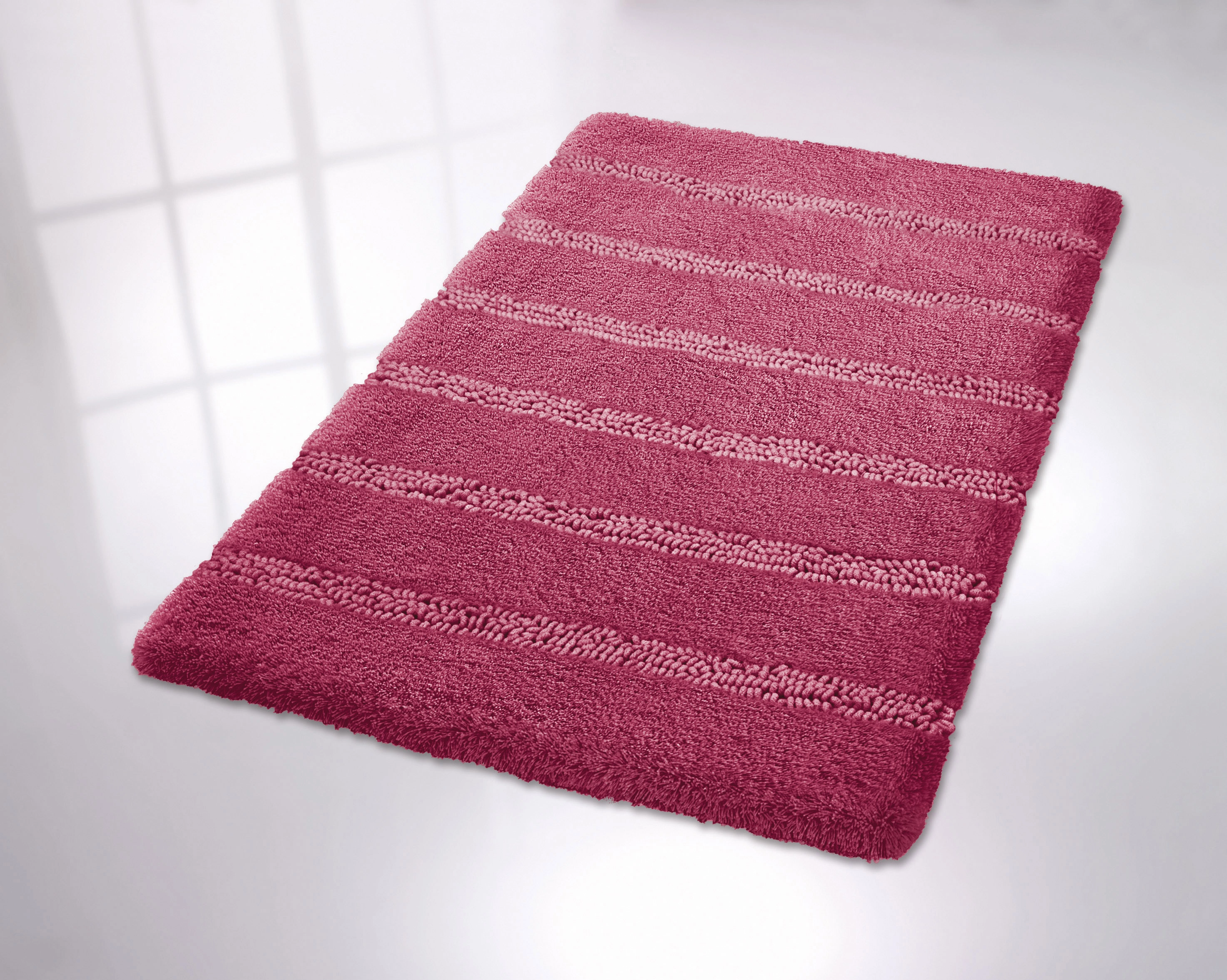 Roter Badteppich mit Streifenmuster auf hellem Boden. Weiche Textur, ideal für Badezimmer.