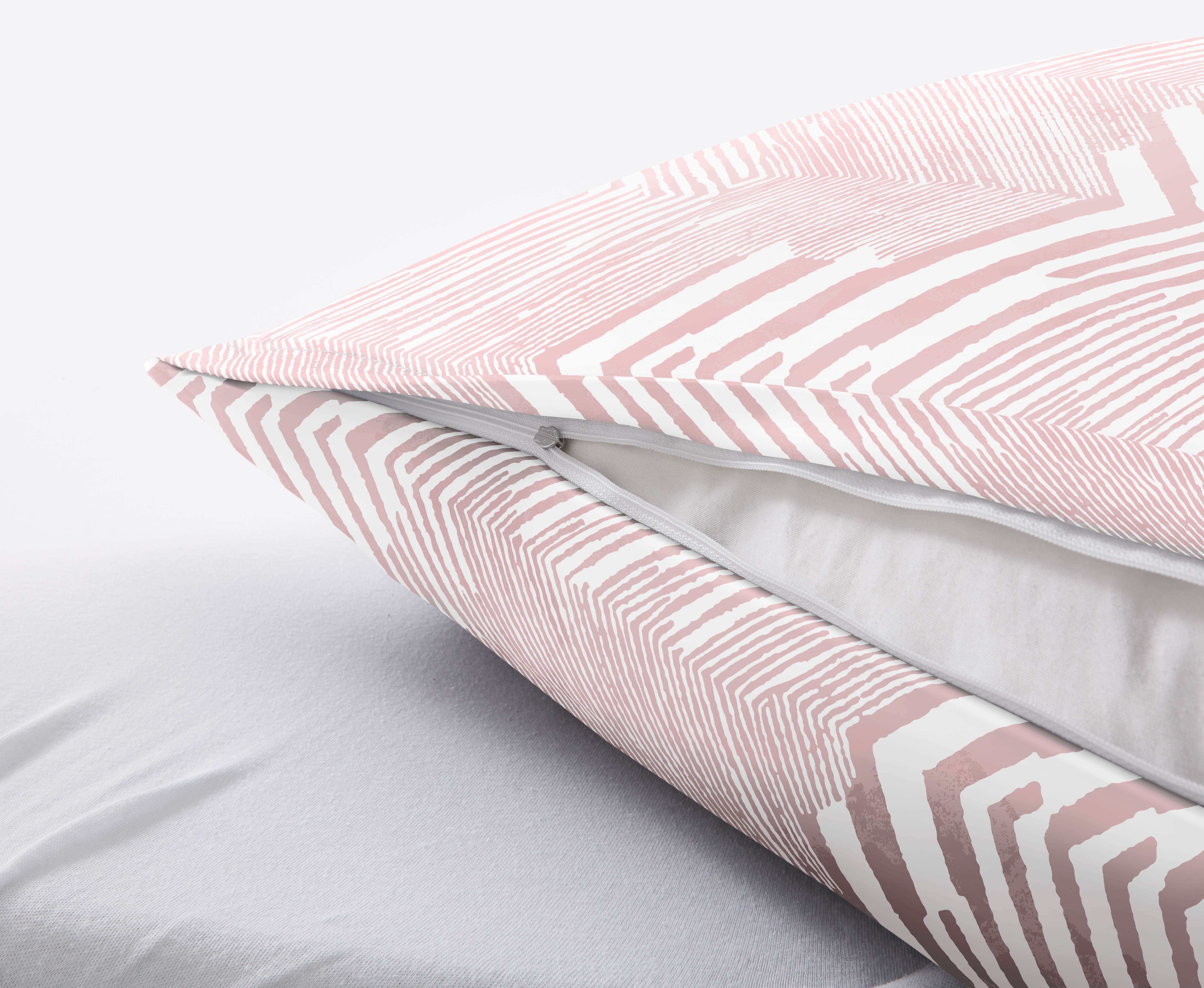 Nahaufnahme eines Kissens mit geometrischem Muster in Rosa und Weiß, sichtbarer Reißverschluss, weiche Textur.