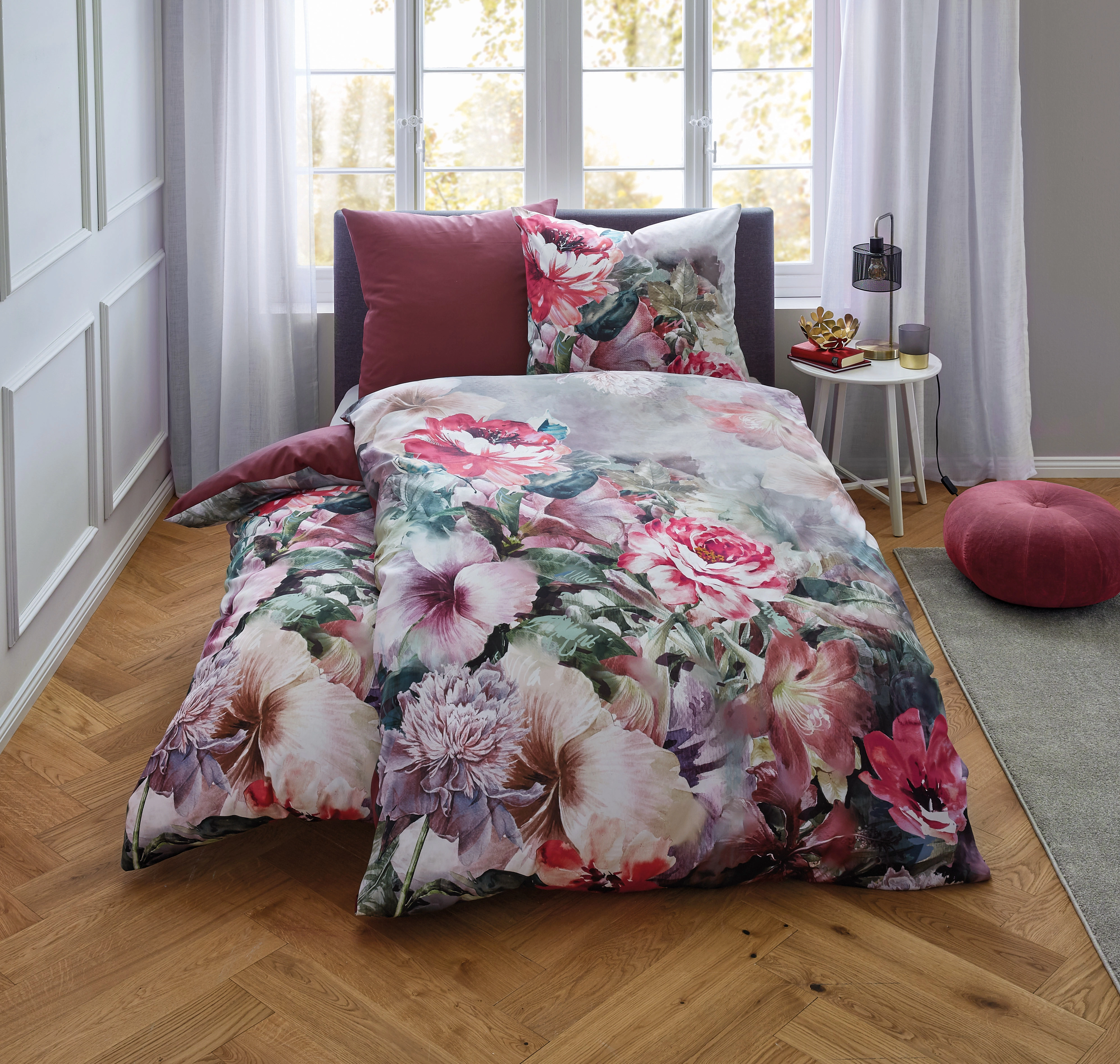 Bettwäsche-Set mit floralem Muster in Rosa- und Grüntönen, dekoriert auf einem Bett in einem hellen, modernen Schlafzimmer.