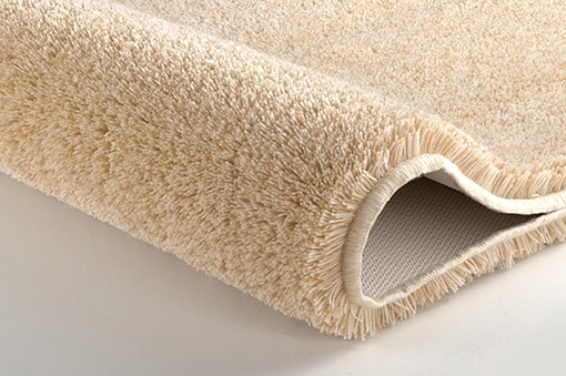Beiger, flauschiger Teppich mit rutschfester Unterseite, ideal für Badezimmer.