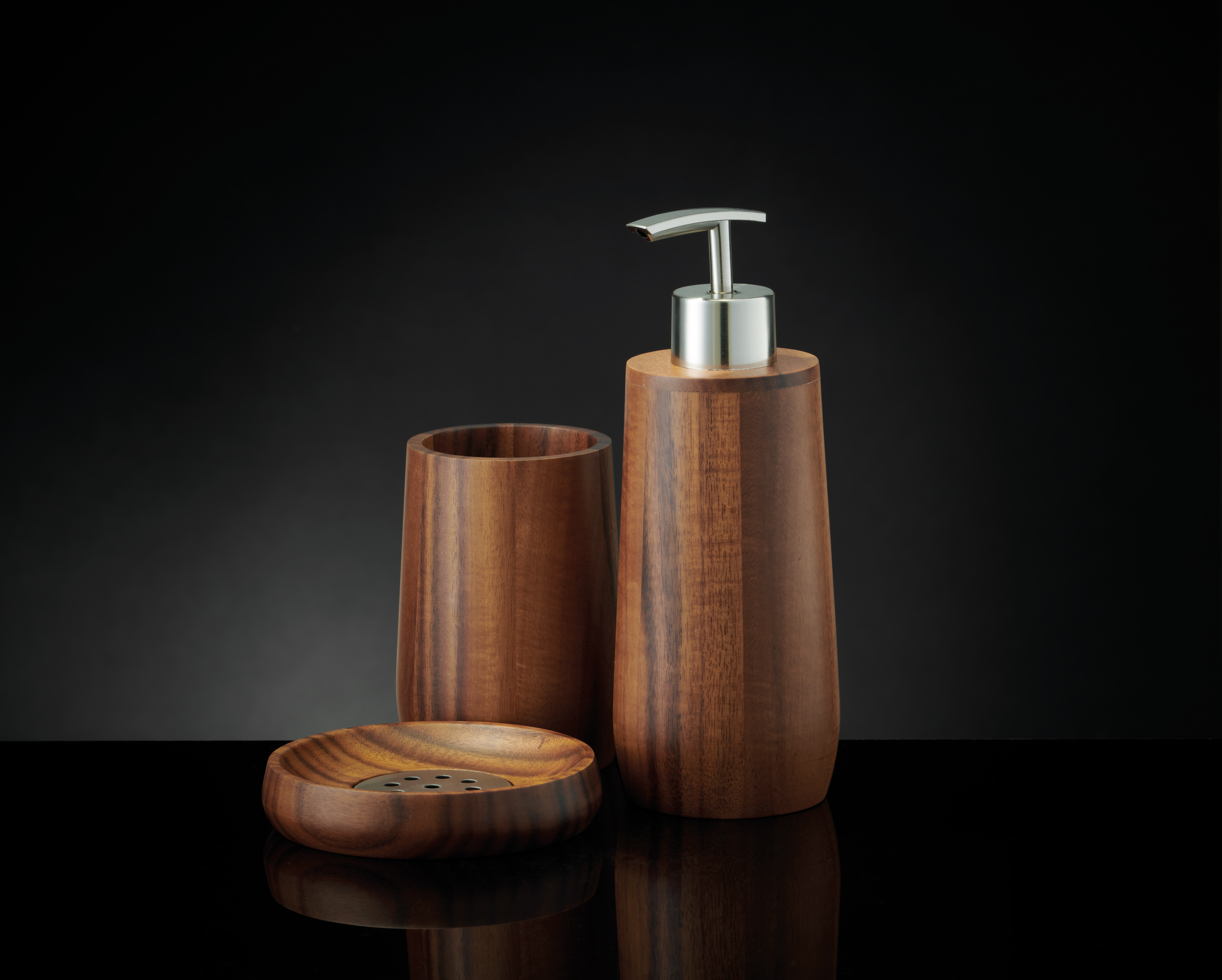 Elegantes Bad-Set aus Holz mit Seifenspender, Zahnbürstenhalter und Seifenschale vor schwarzem Hintergrund.
