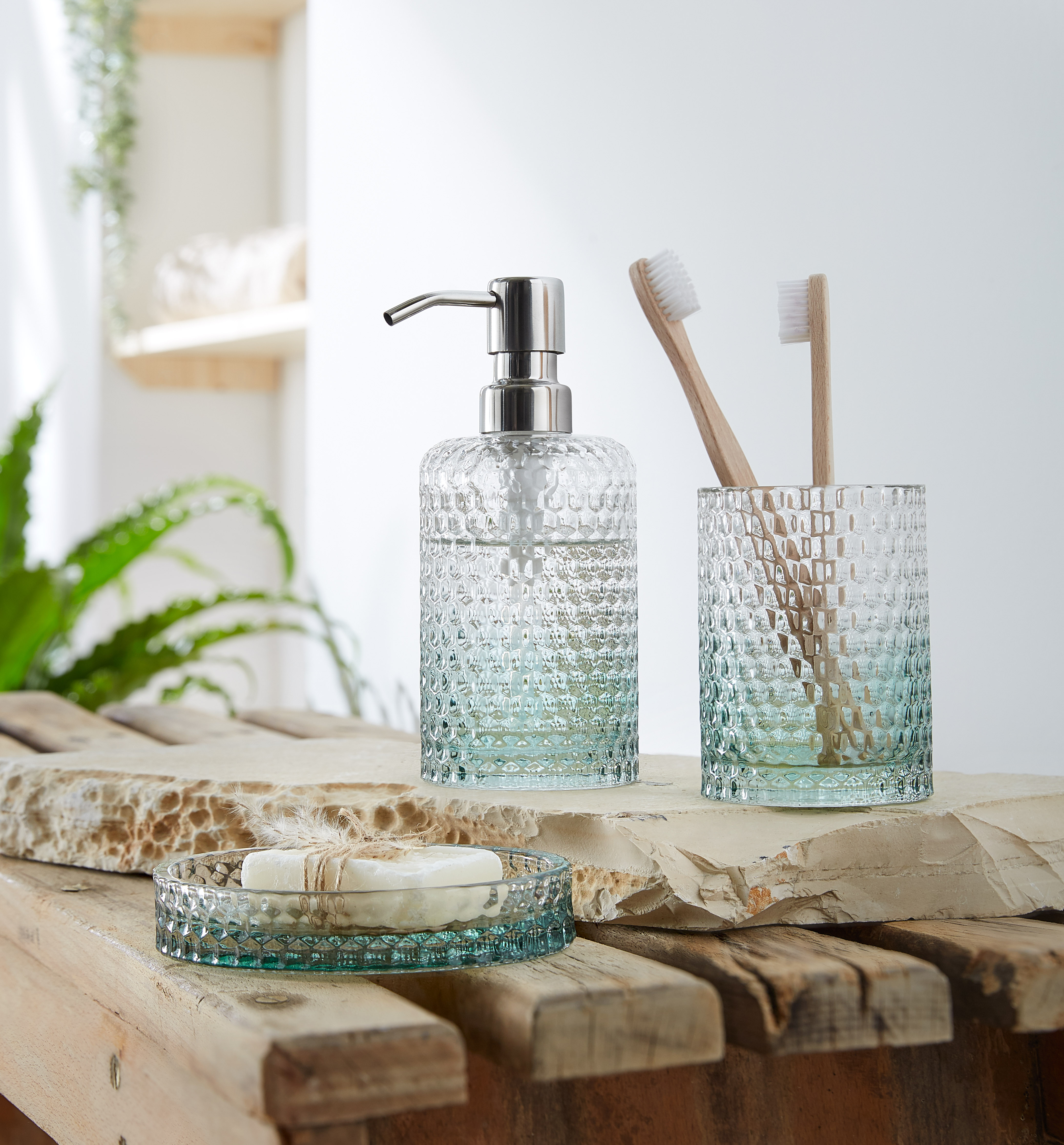 Elegantes Badezimmer-Set aus Glas mit Seifenspender, Zahnbürstenhalter und Seifenschale in modernem Design.