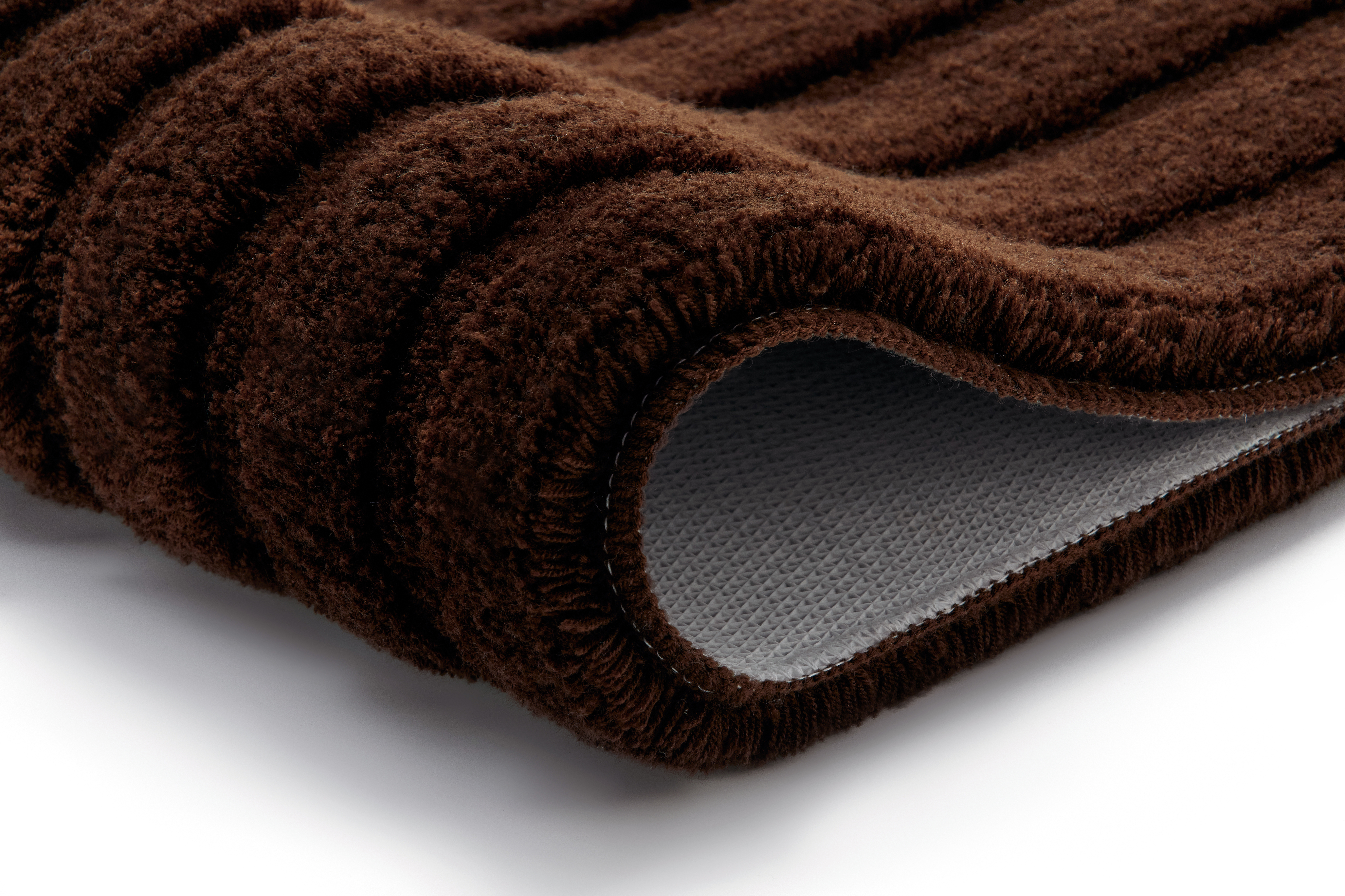 Brauner, flauschiger Badteppich mit rutschfester Unterseite, Nahaufnahme der Textur und Kanten.