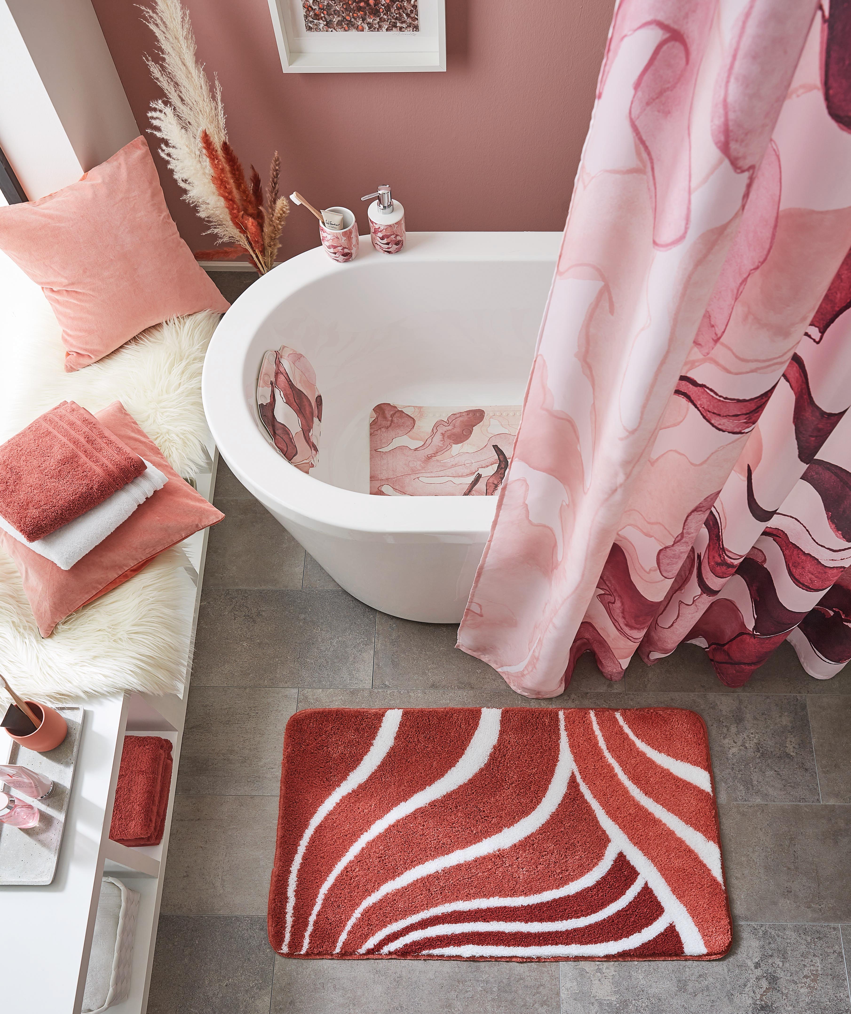 Modernes Badezimmer mit rosa Akzenten, Badewanne, Duschvorhang mit Wellenmuster, passendem Teppich und dekorativen Accessoires.