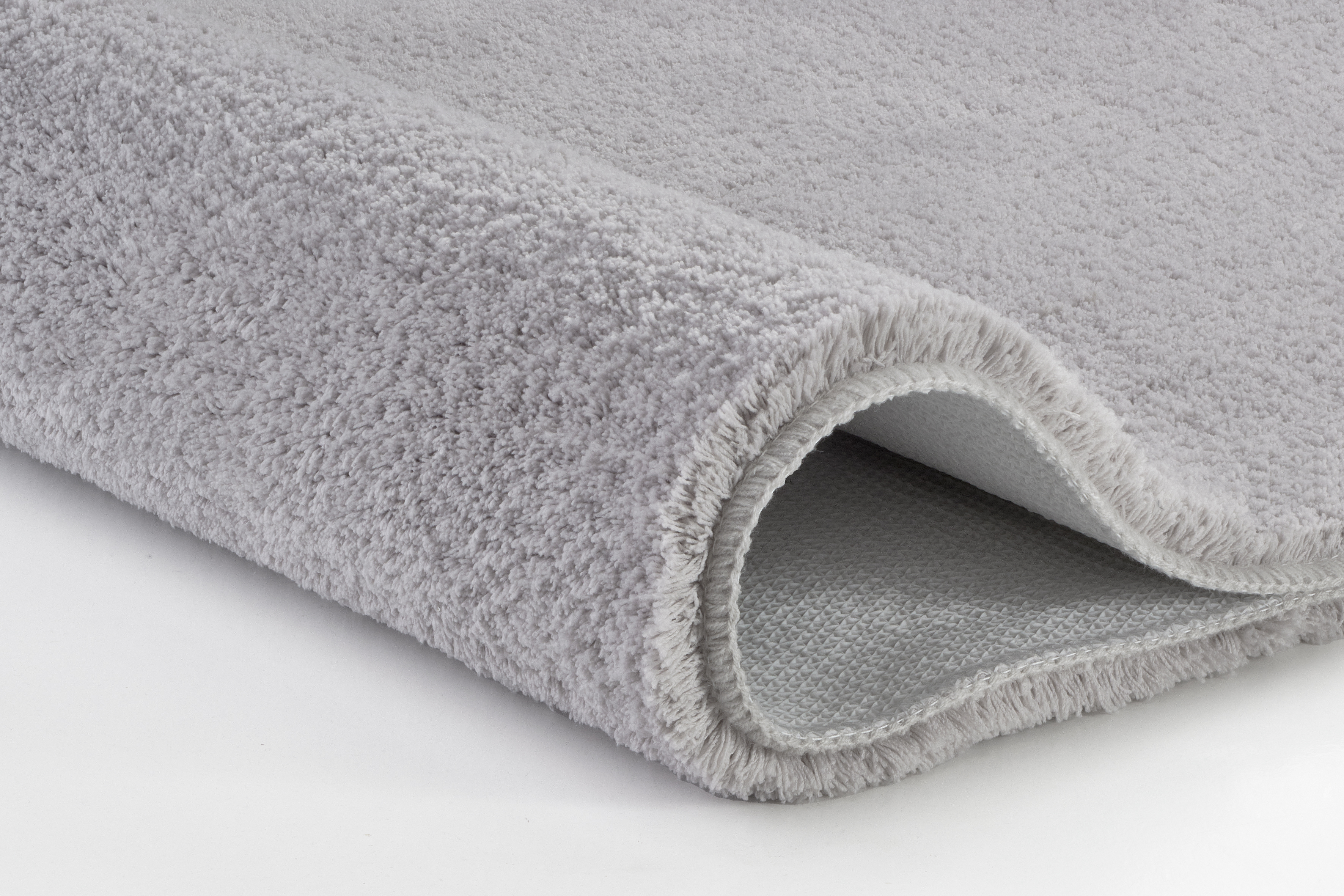 Grauer, flauschiger Teppich mit weicher Oberfläche und rutschfester Unterseite, ideal für Badezimmer und Wohnräume.
