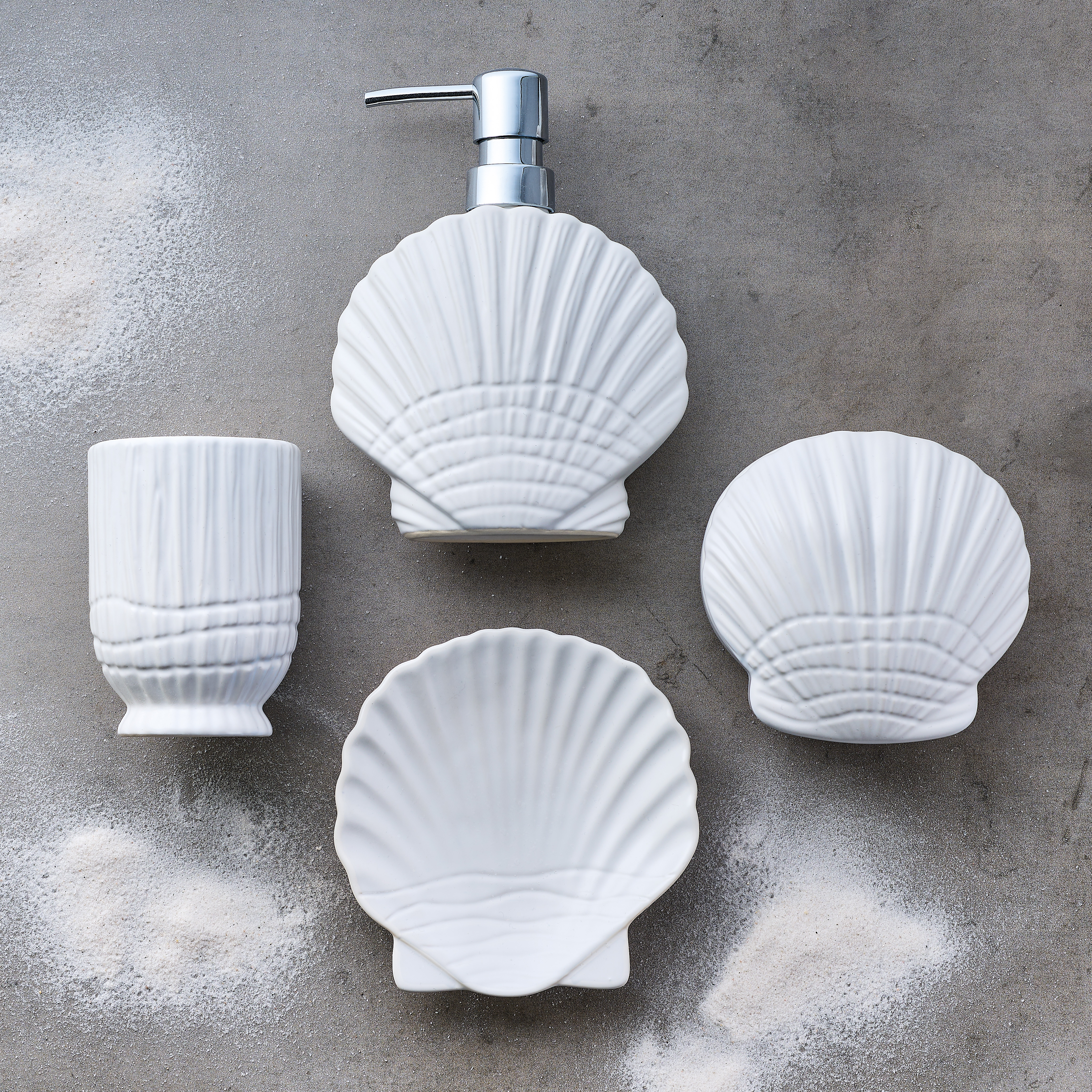 Set aus weißer Badezimmer-Keramik in Muschelform, bestehend aus Seifenspender, Zahnbürstenhalter, Seifenschale und Schälchen.
