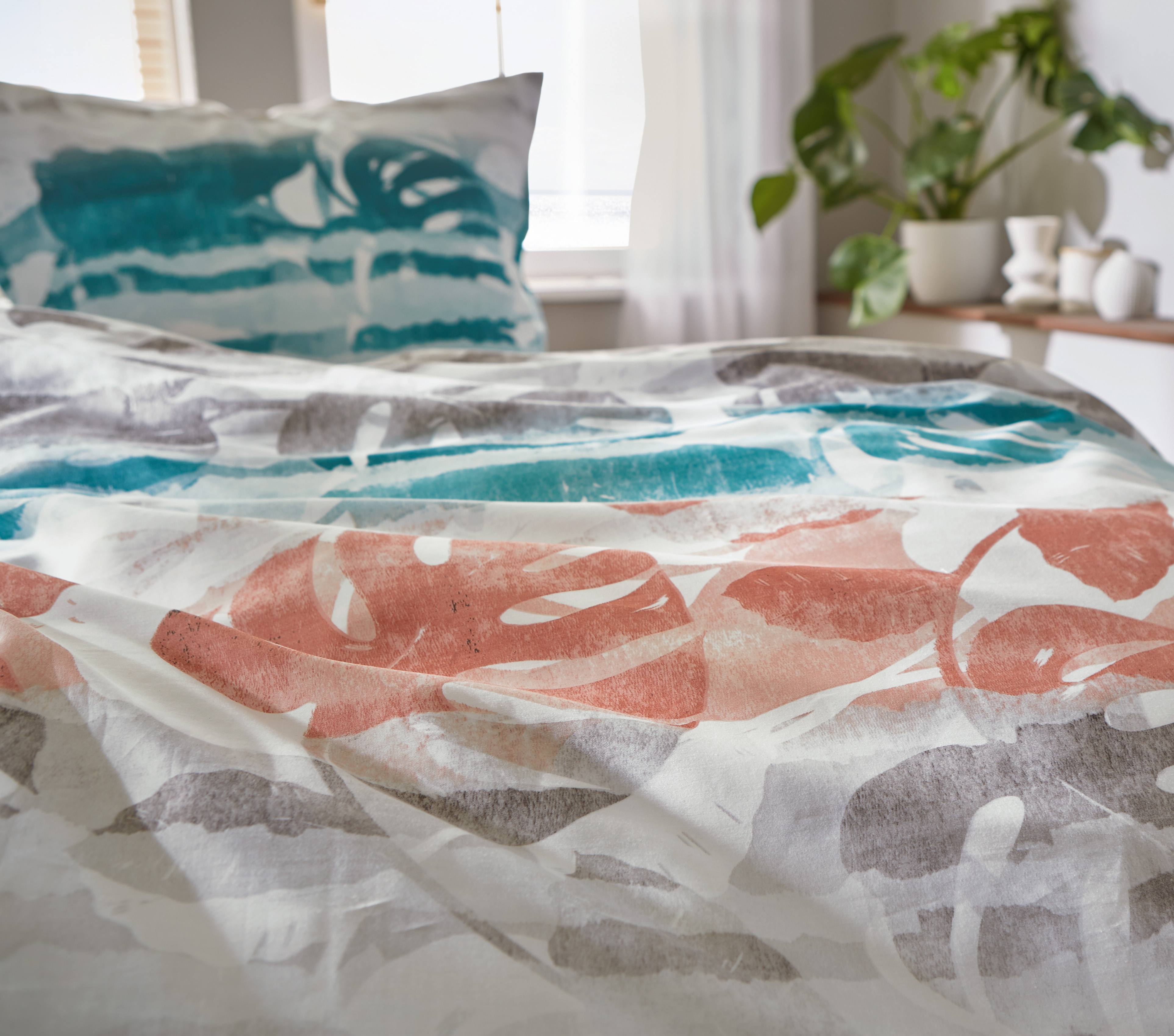 Bettwäsche-Set mit tropischem Blattmuster in Blau, Grau und Koralle, aus weichem Material, ideal für ein stilvolles Schlafzimmer.