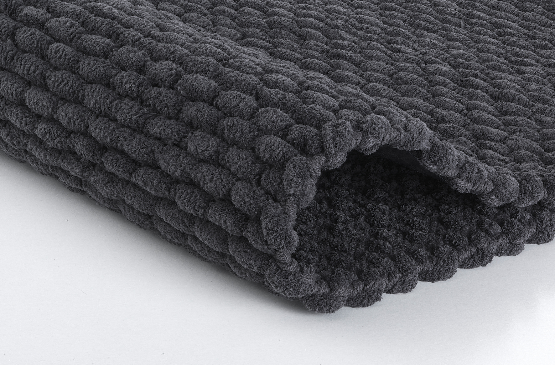 Dunkelgrauer, flauschiger Badteppich mit strukturierter Oberfläche, ideal für ein modernes Badezimmer.