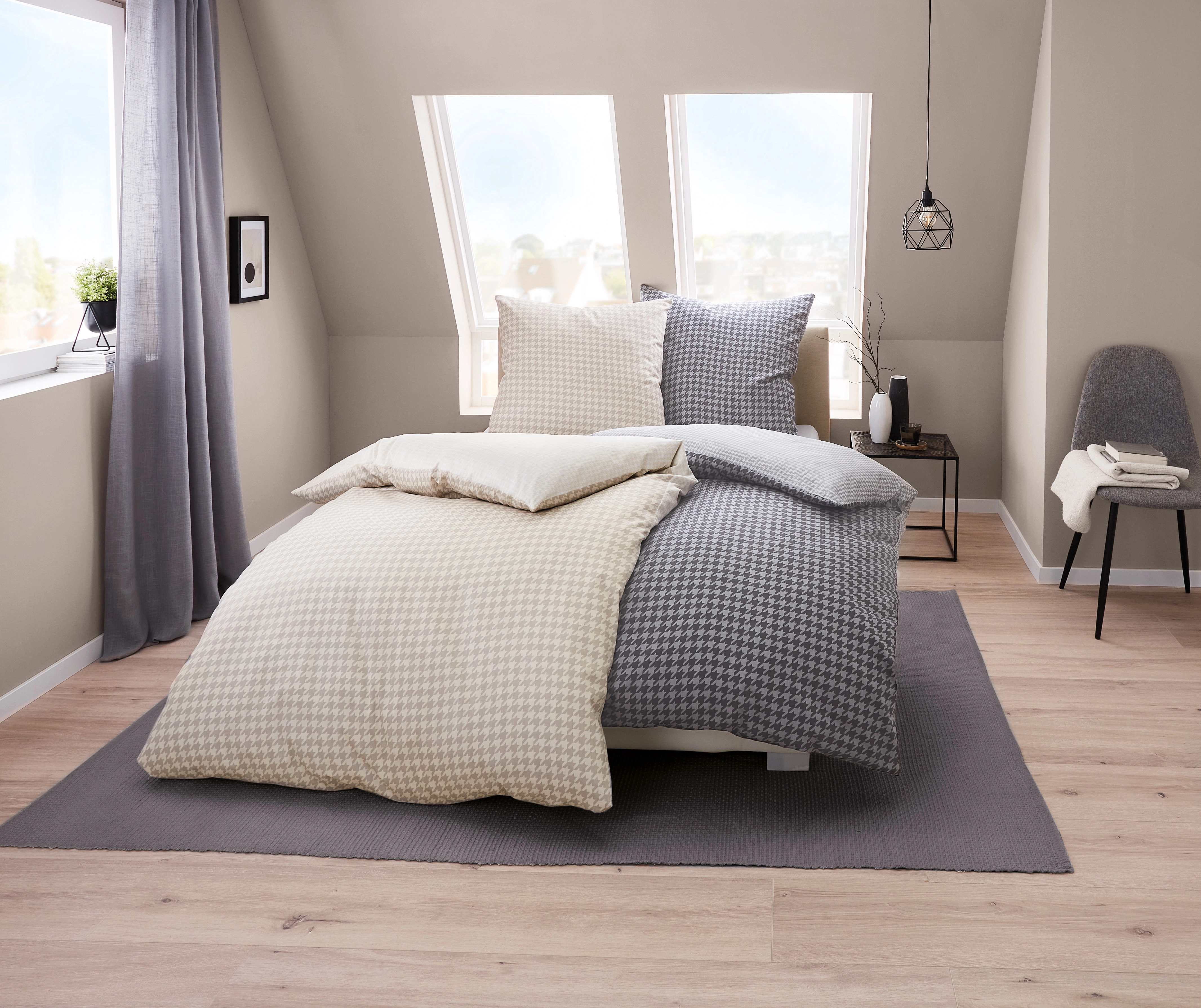 Bettwäsche-Set in Beige und Grau mit Hahnentrittmuster, gemütlich arrangiert in modernem Schlafzimmer mit Dachfenster.