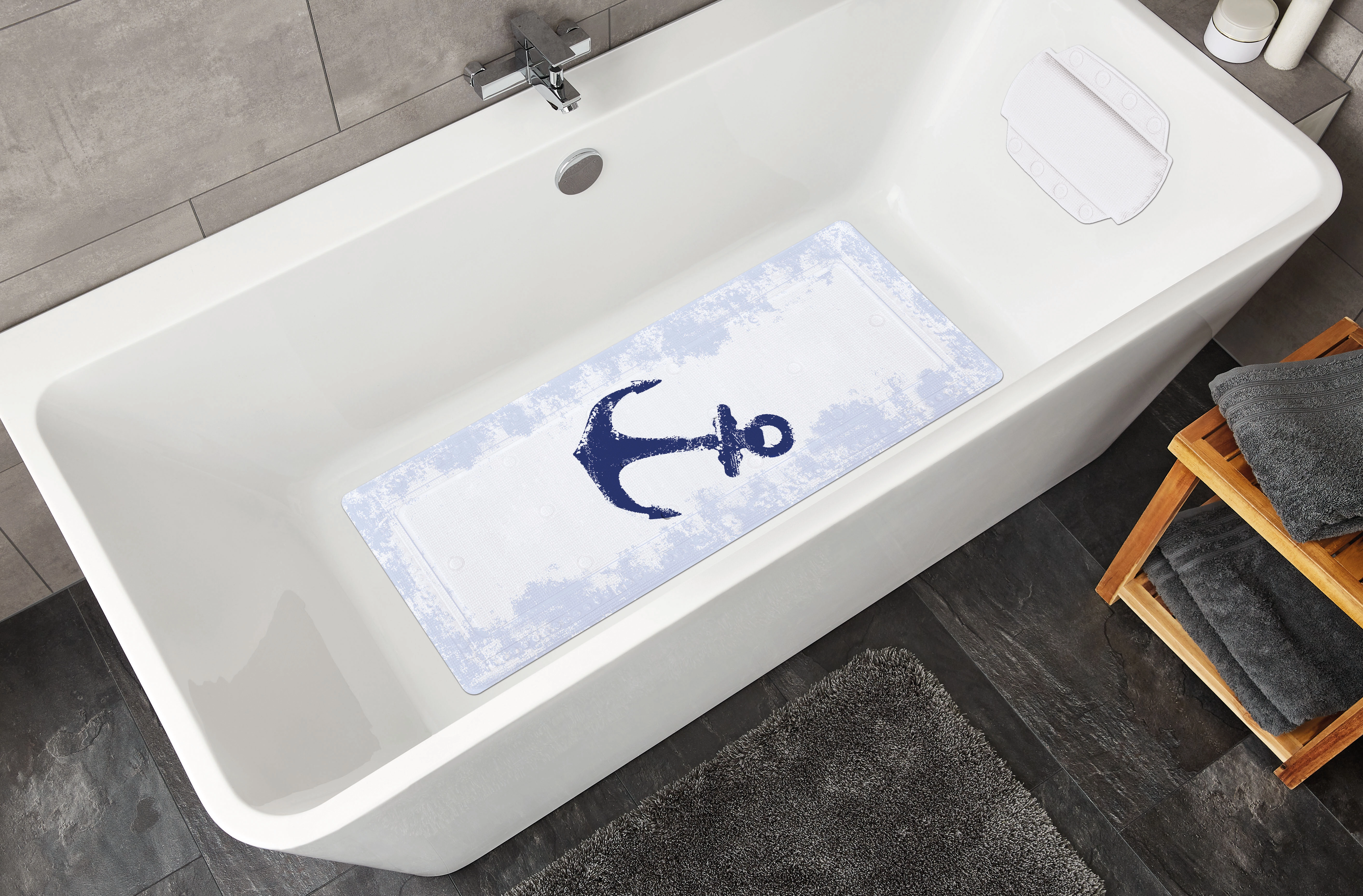 Weiße Badewanne mit rutschfester Badematte, blauem Anker-Motiv, grauen Handtüchern und modernem Badezimmerdekor.