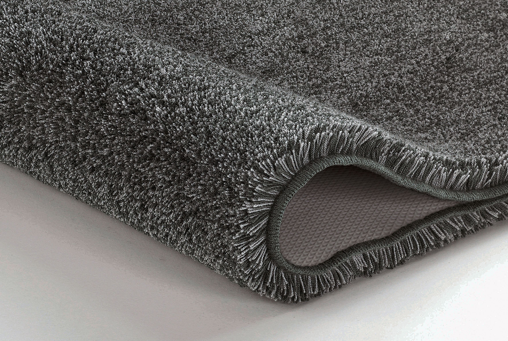 Grauer, flauschiger Badteppich mit rutschfester Unterseite, ideal für ein gemütliches und sicheres Badezimmer.
