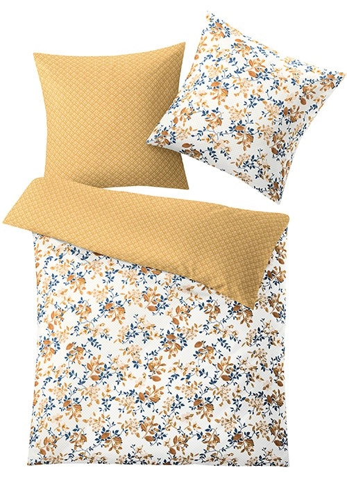 Bettwäsche-Set mit floralen Mustern in Blau und Braun auf weißem Hintergrund, Rückseite in warmem Gelbton. Kissen- und Deckenbezug.