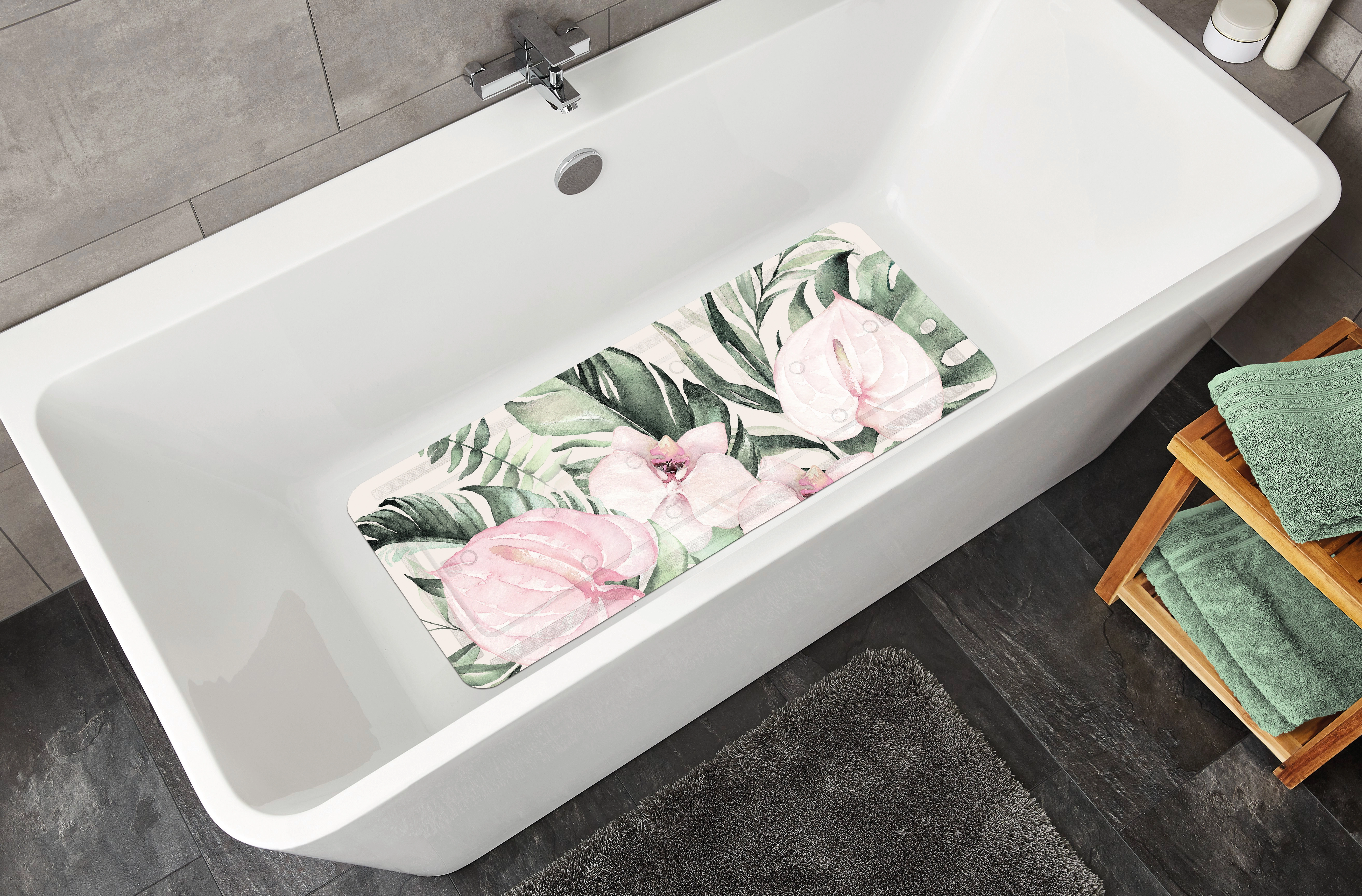 Badezimmer mit weißer Badewanne und rutschfester Badematte mit tropischem Blumenmuster in Rosa und Grün.