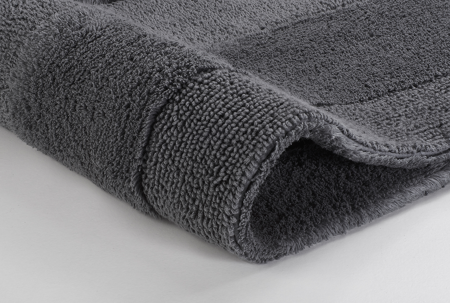 Grauer, flauschiger Badteppich mit weicher Textur und dezentem Streifenmuster, ideal für ein modernes Badezimmer.