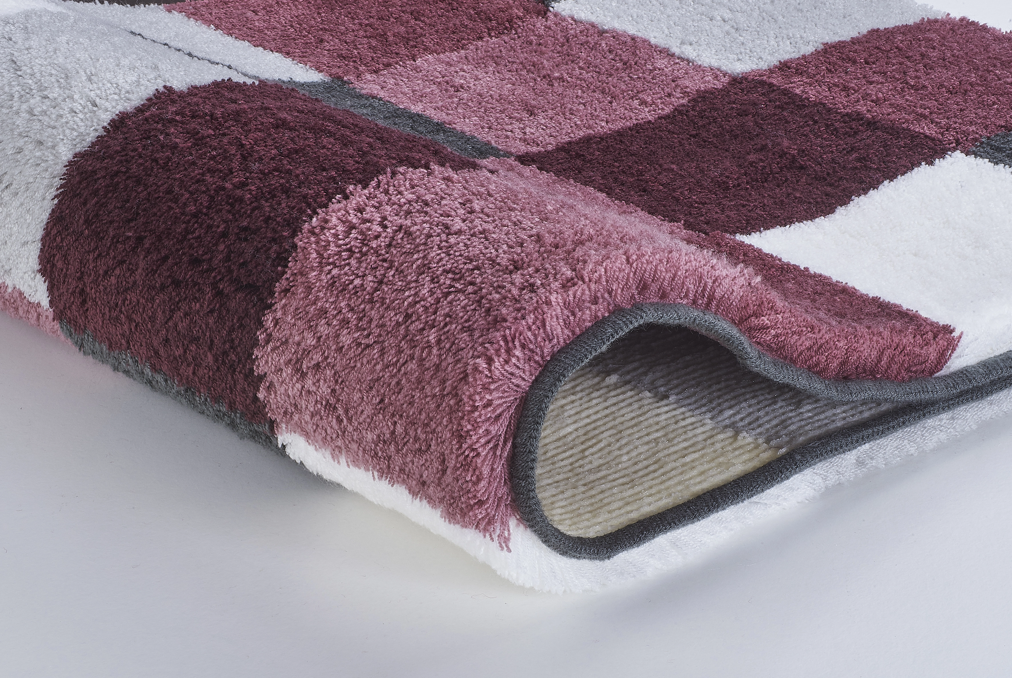 Badematte mit Karomuster in verschiedenen Rottönen, weiche Textur, rutschfeste Unterseite, ideal für Badezimmer.