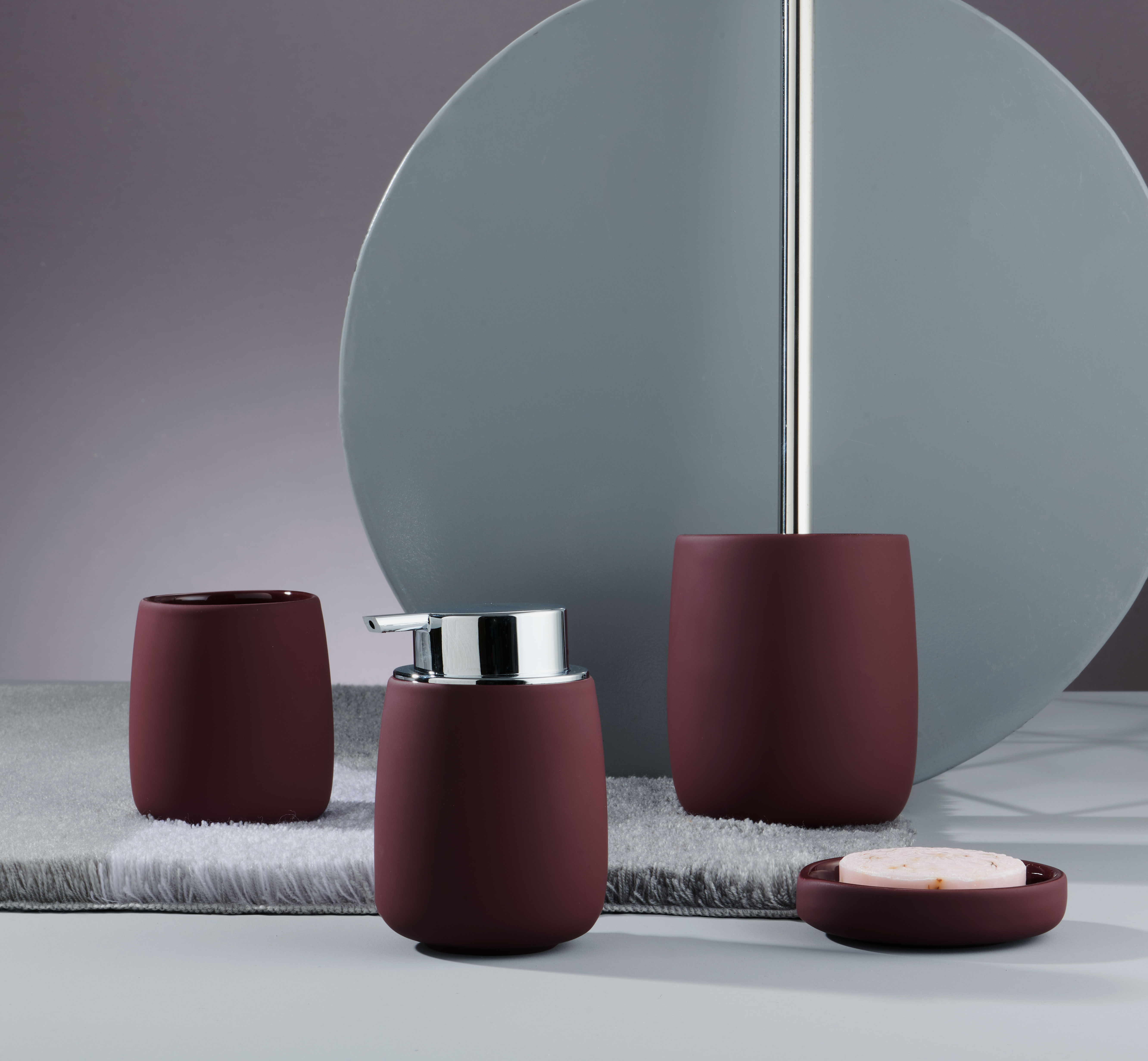 Elegantes Badezimmer-Set in Bordeaux: Seifenspender, Zahnputzbecher und Seifenschale auf grauem Hintergrund.