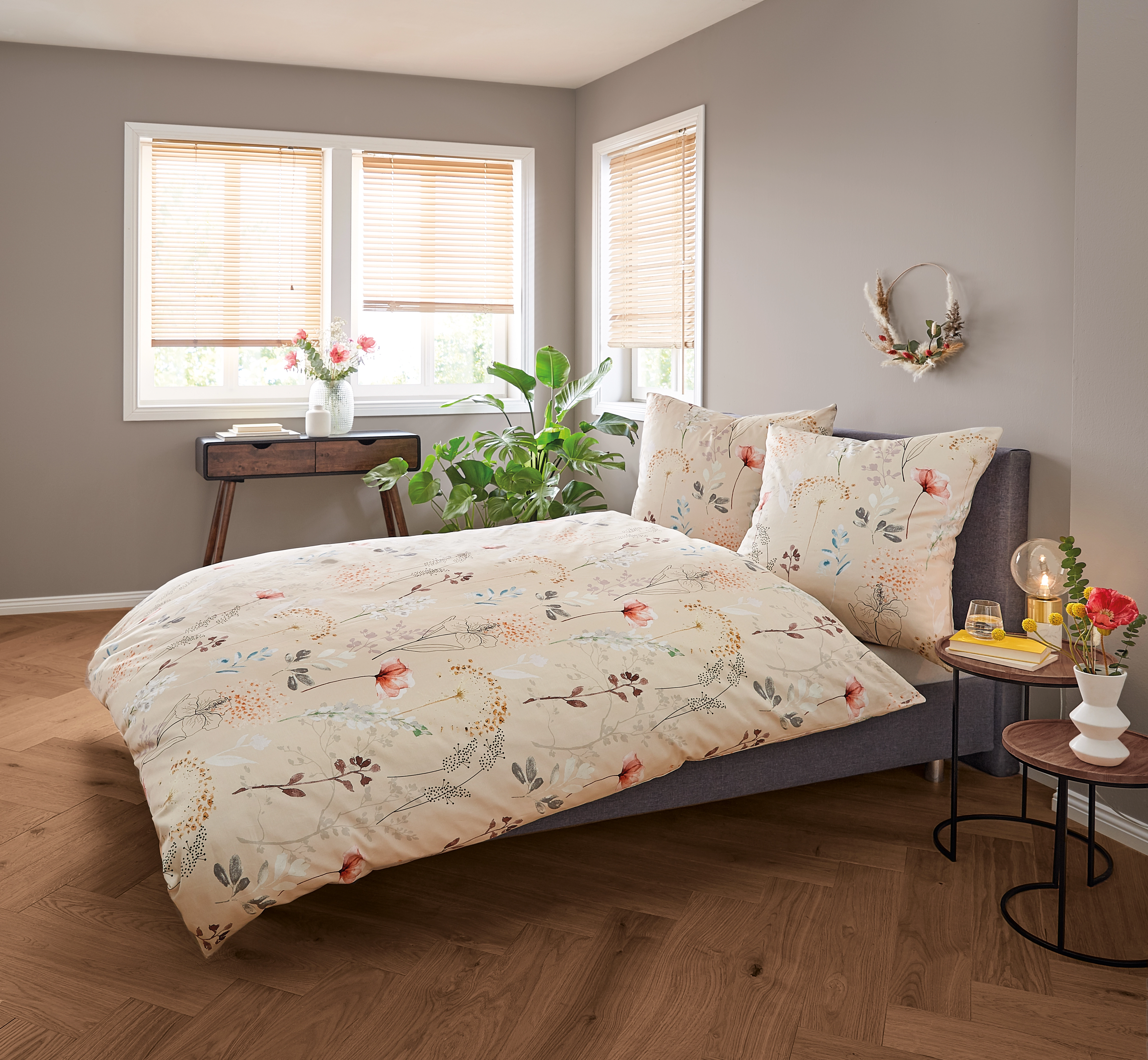 Bettwäsche-Set mit floralem Muster in einem gemütlichen Schlafzimmer mit Pflanzen und Holzmöbeln.