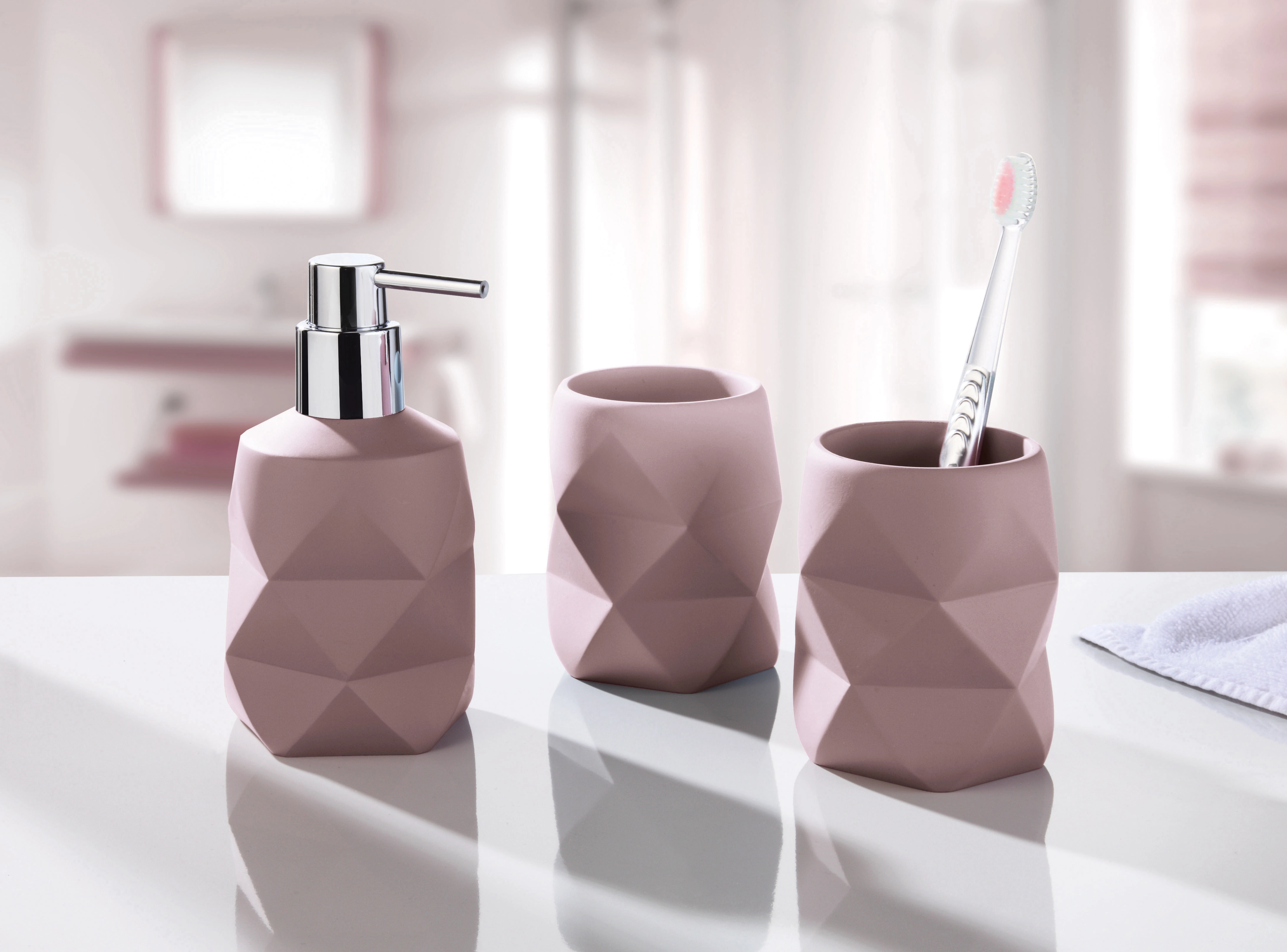 Rosa Badezimmer-Set mit Seifenspender und zwei Zahnbürstenhaltern in modernem, geometrischem Design.